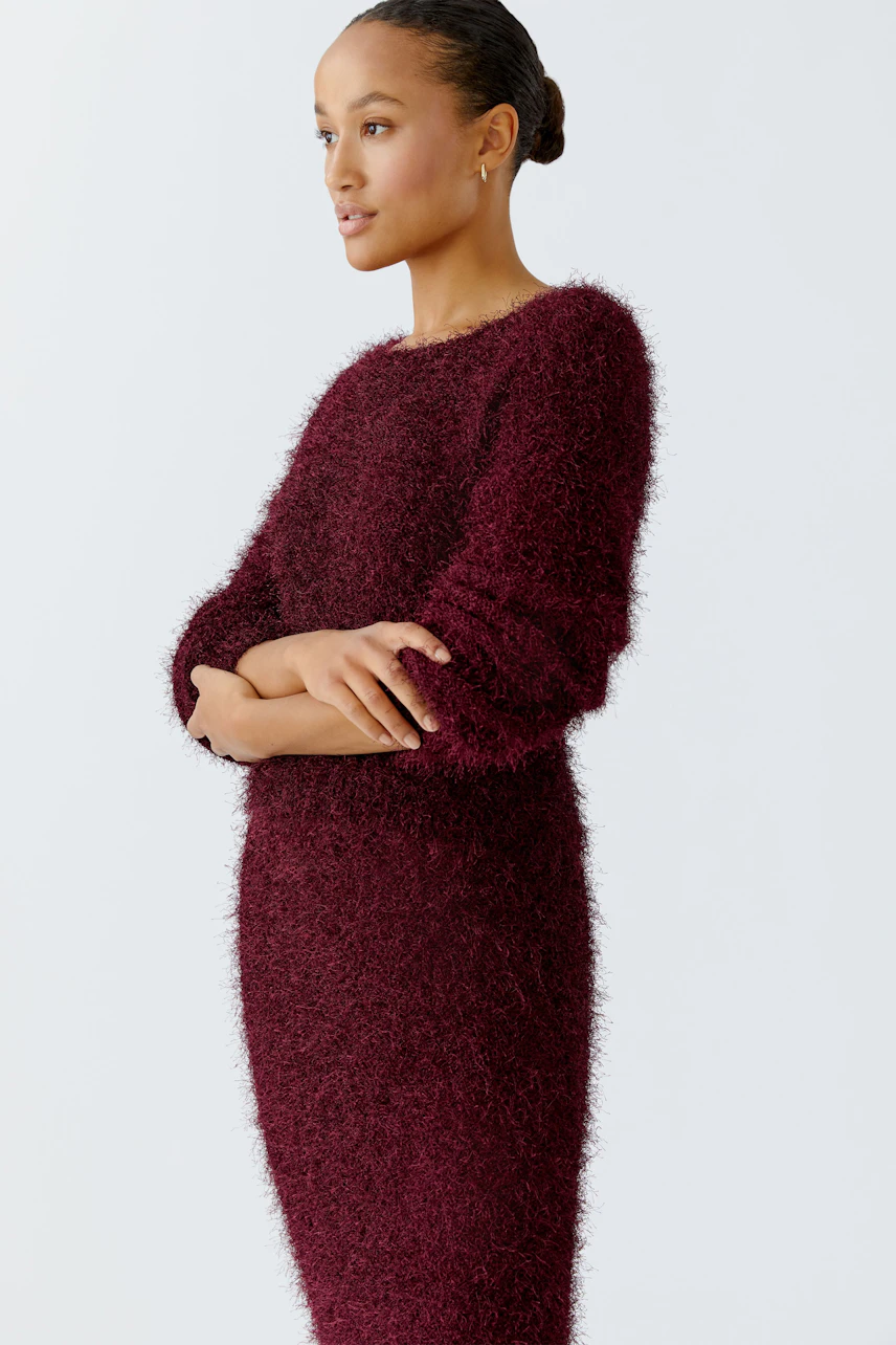 Damen-Pullover: Frau in einem weichen, burgunderfarbenen Pullover mit lässigem Schnitt und langen Ärmeln.