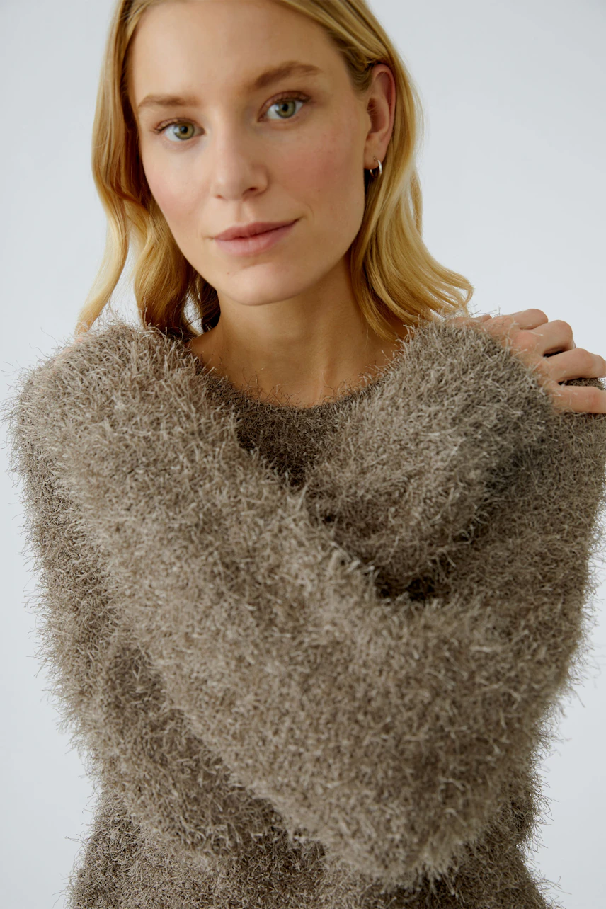 Cozy women's pullover: A woman in a soft, fuzzy brown pullover with relaxed sleeves.