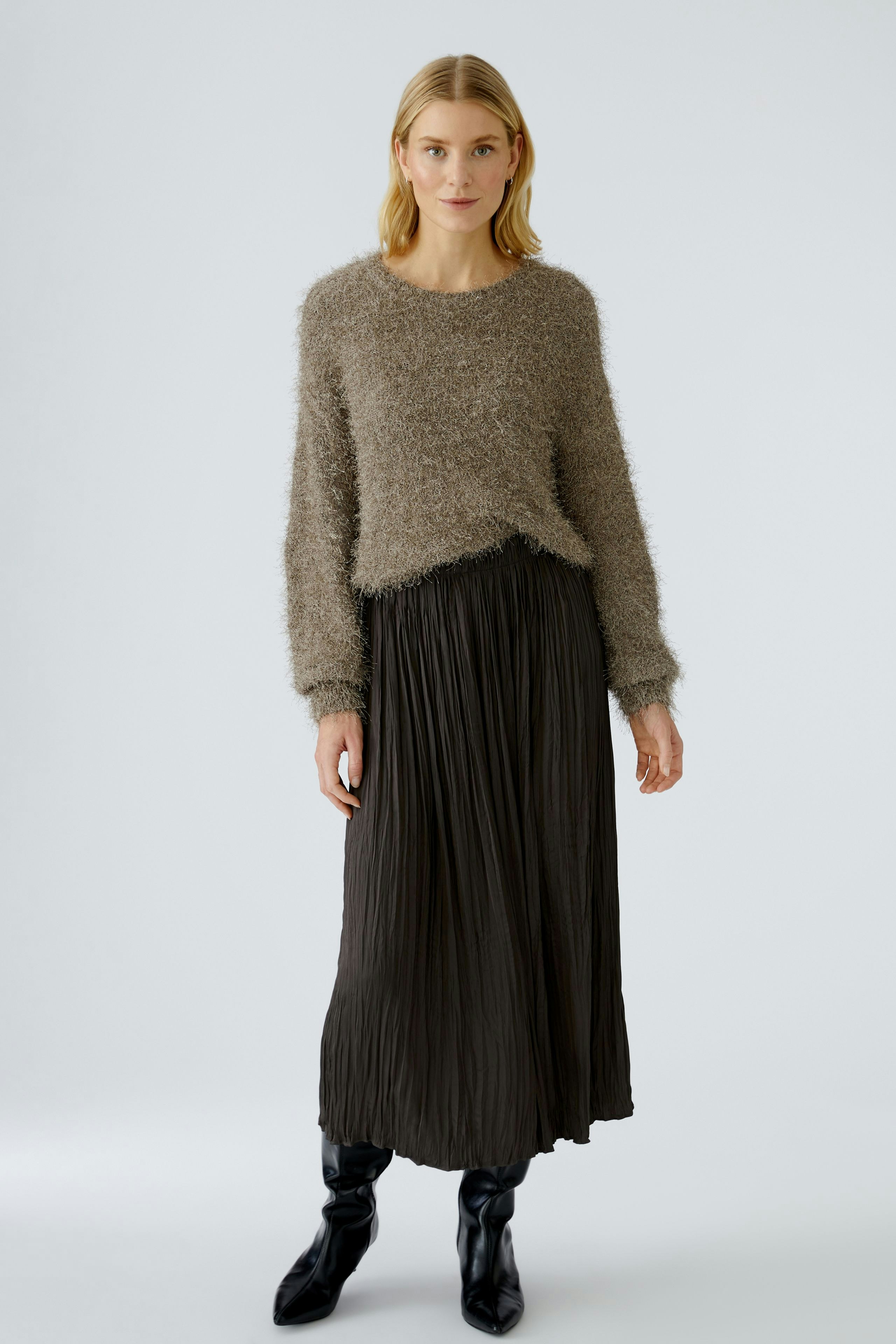 Casual women's pullover: A woman in a soft, fuzzy brown pullover paired with a pleated skirt.