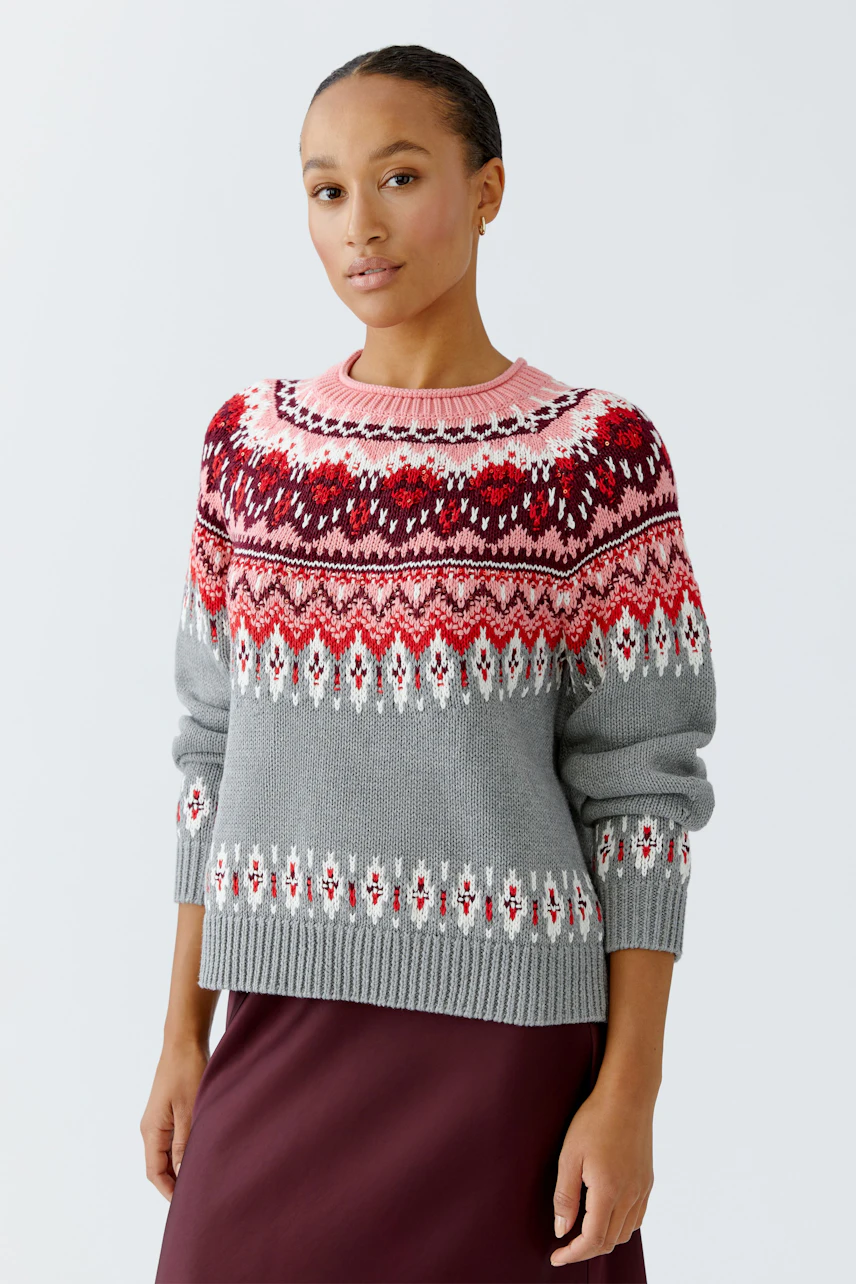 Casual women's pullover: Young woman in a grey patterned pullover with vibrant colors and relaxed fit.