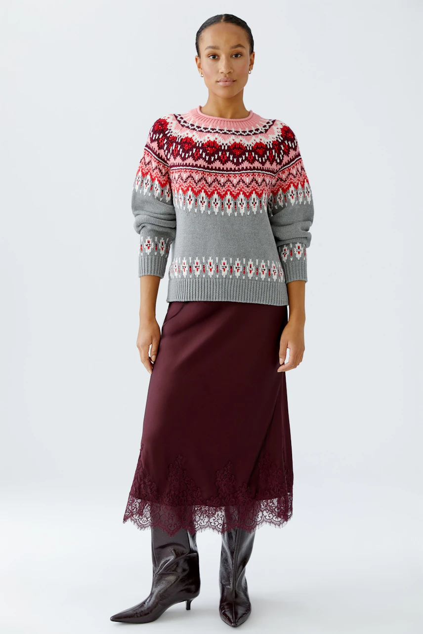 Casual women's pullover: Woman in a colorful patterned pullover paired with a burgundy skirt.