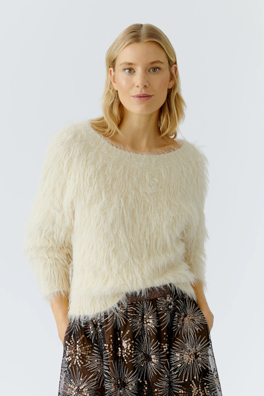 Cozy women's pullover: A woman in a fluffy cream pullover paired with a patterned skirt.