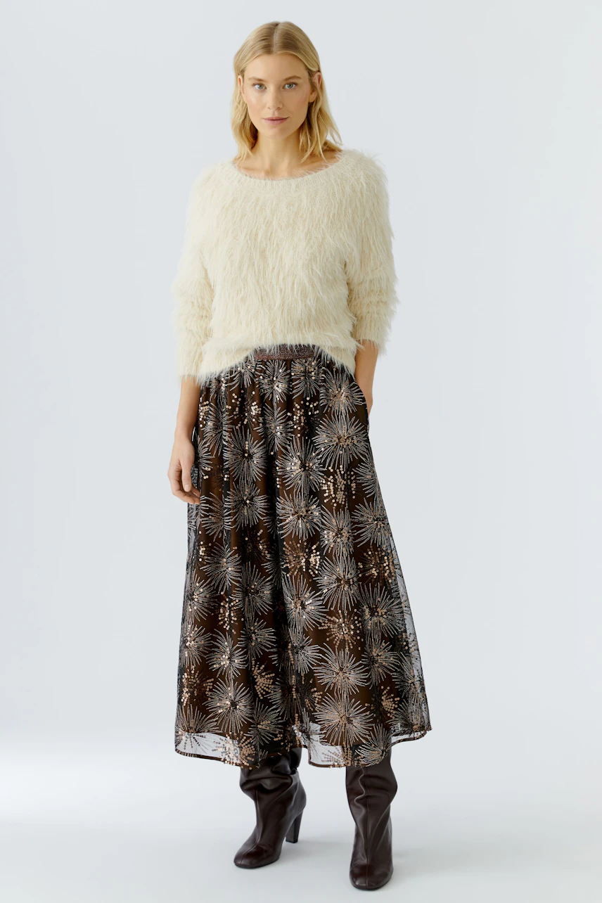 Cozy women's pullover: A woman in a fluffy cream pullover paired with a patterned skirt.