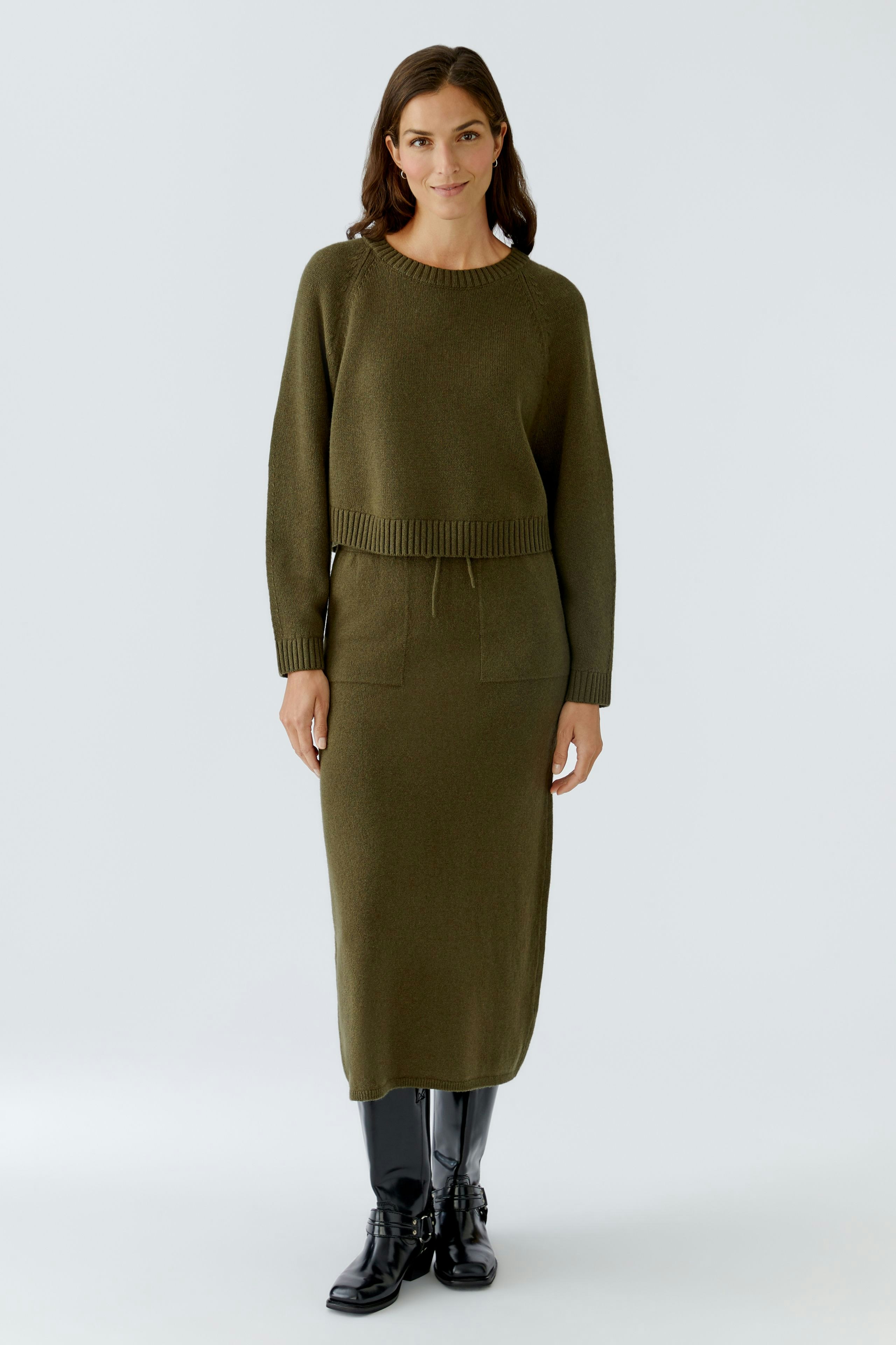 Casual women's pullover: A woman in an olive green pullover with a relaxed fit and ribbed hem.