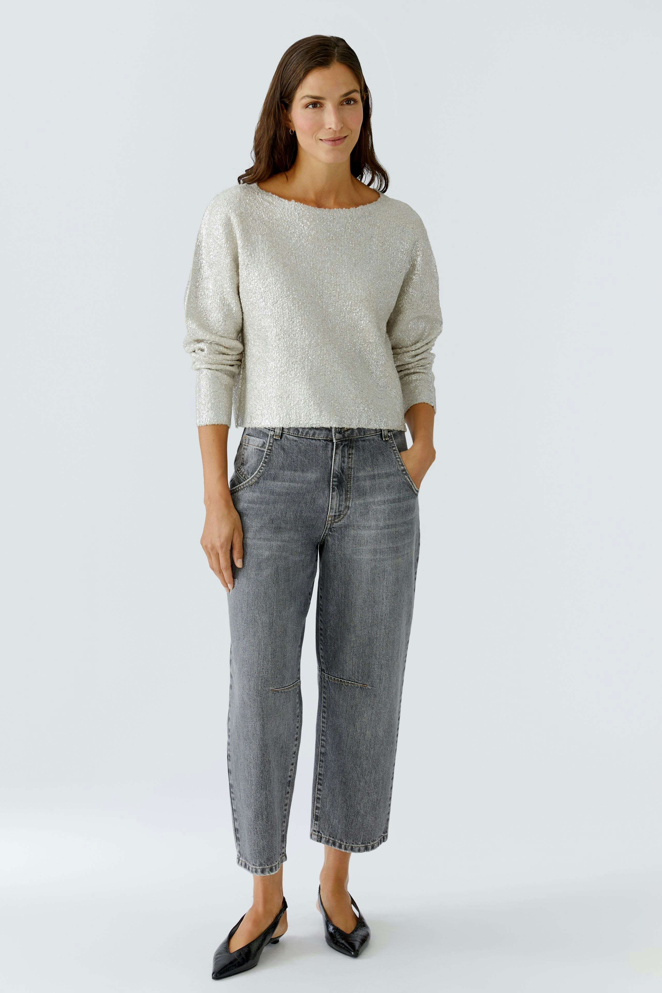 Casual women's pullover: A woman in a light gray pullover with a relaxed fit and jeans.