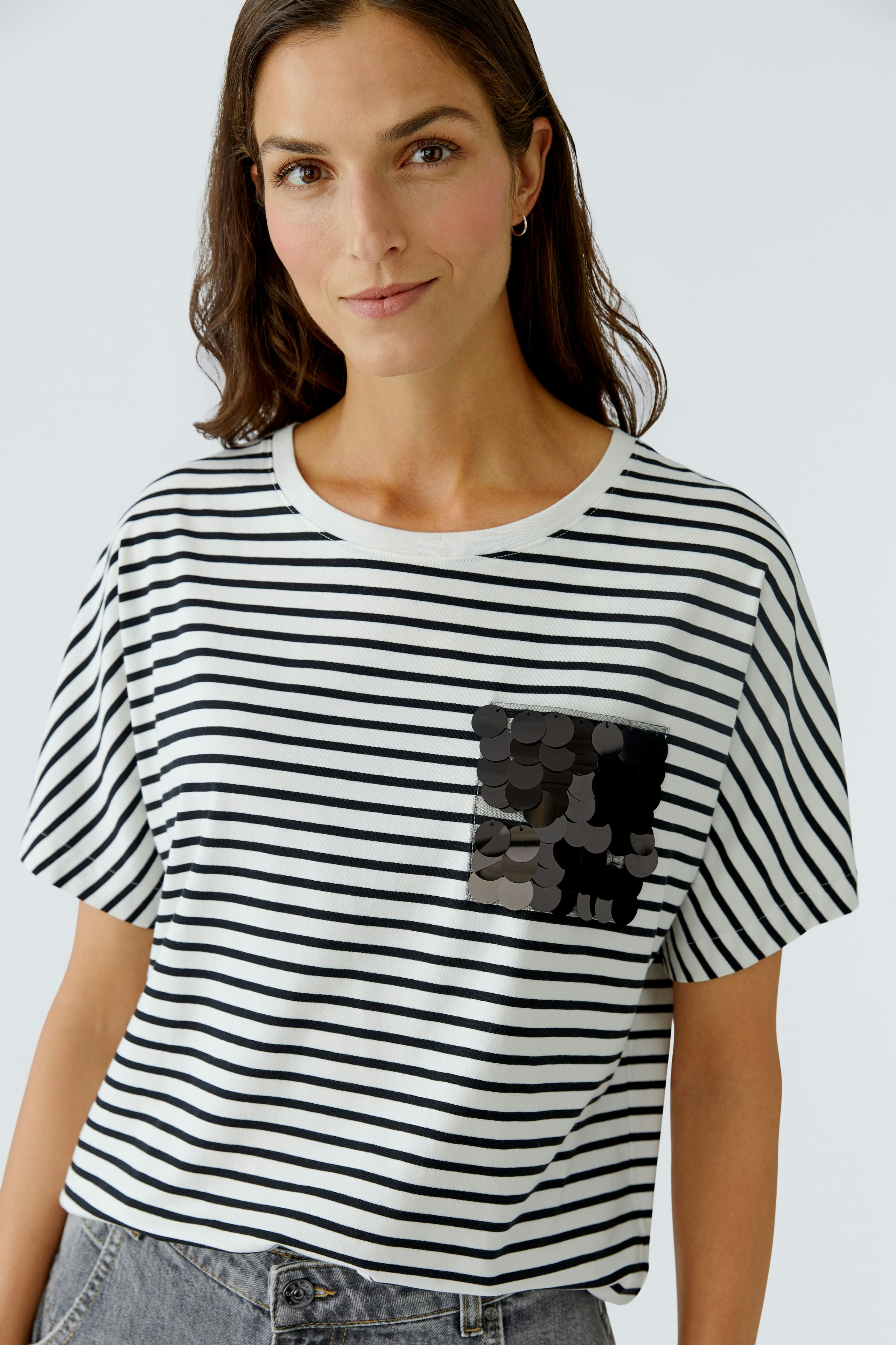 Casual women's T-shirt: Young woman in a striped tee with a decorative pocket, smiling confidently.