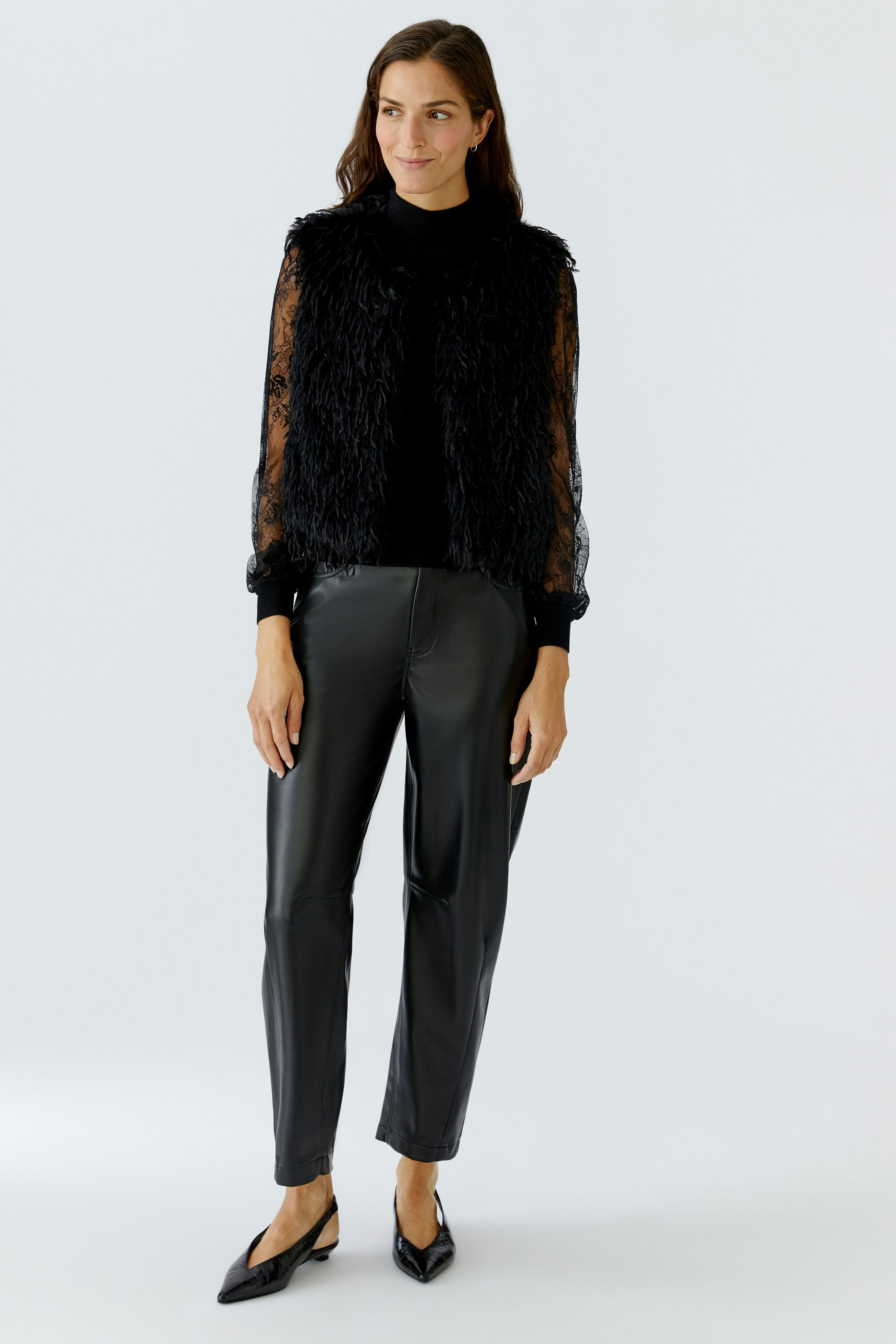 Stylish women's vest: A woman in a black fluffy vest over a top, paired with sleek pants.
