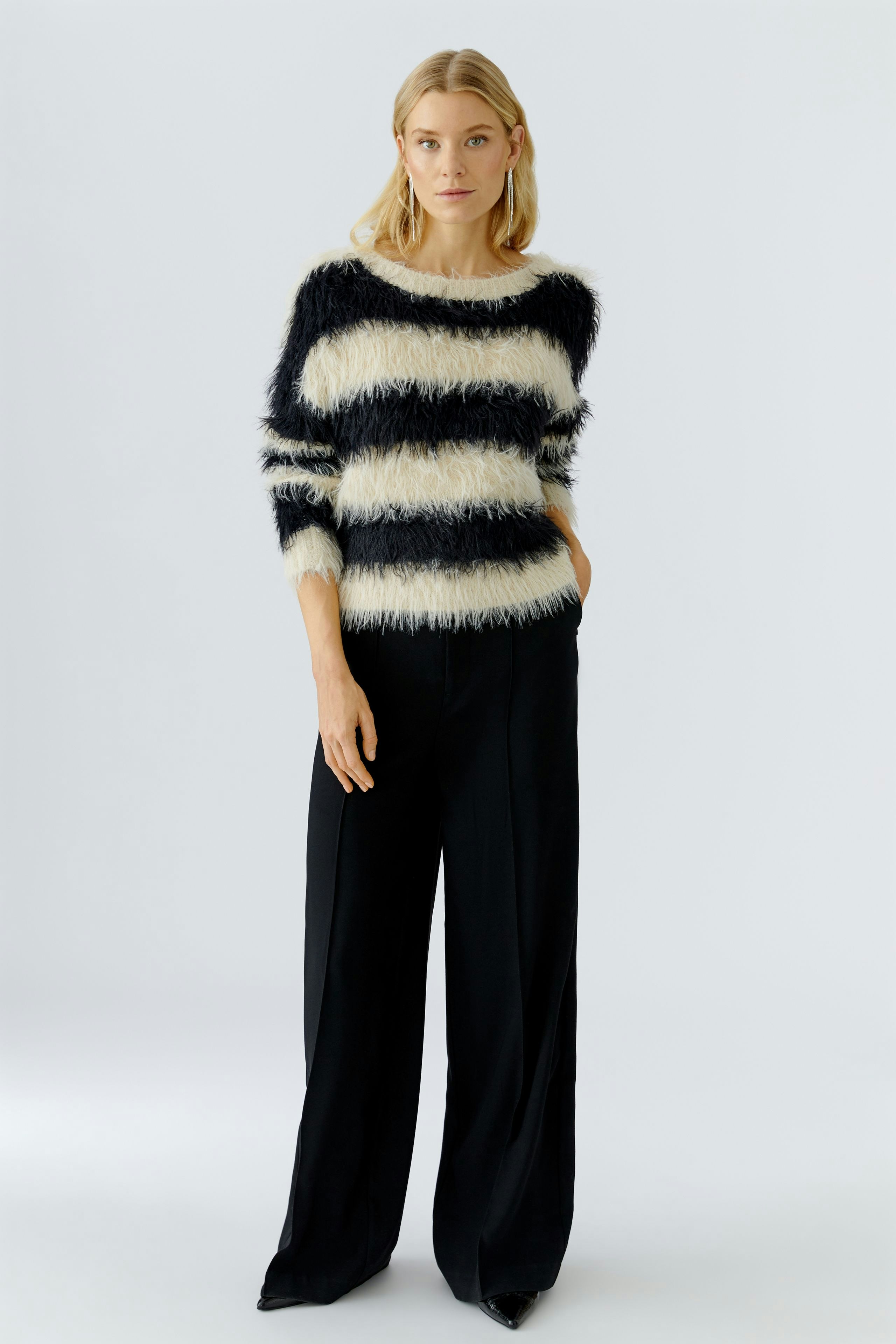 Casual women's pullover: Woman in a striped fluffy pullover with wide sleeves and relaxed fit pants.
