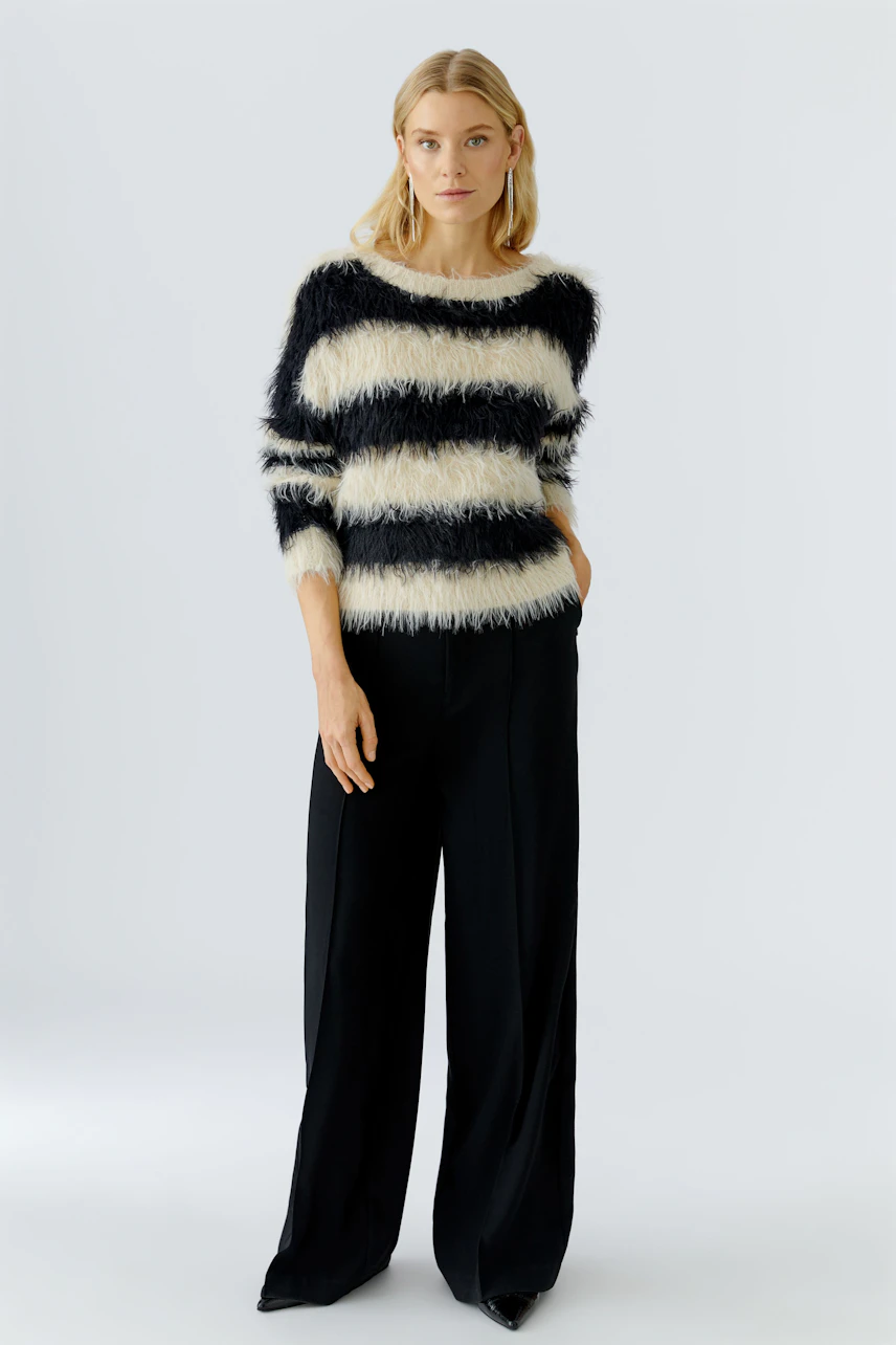 Casual women's pullover: Woman in a striped fluffy pullover with wide sleeves and relaxed fit pants.