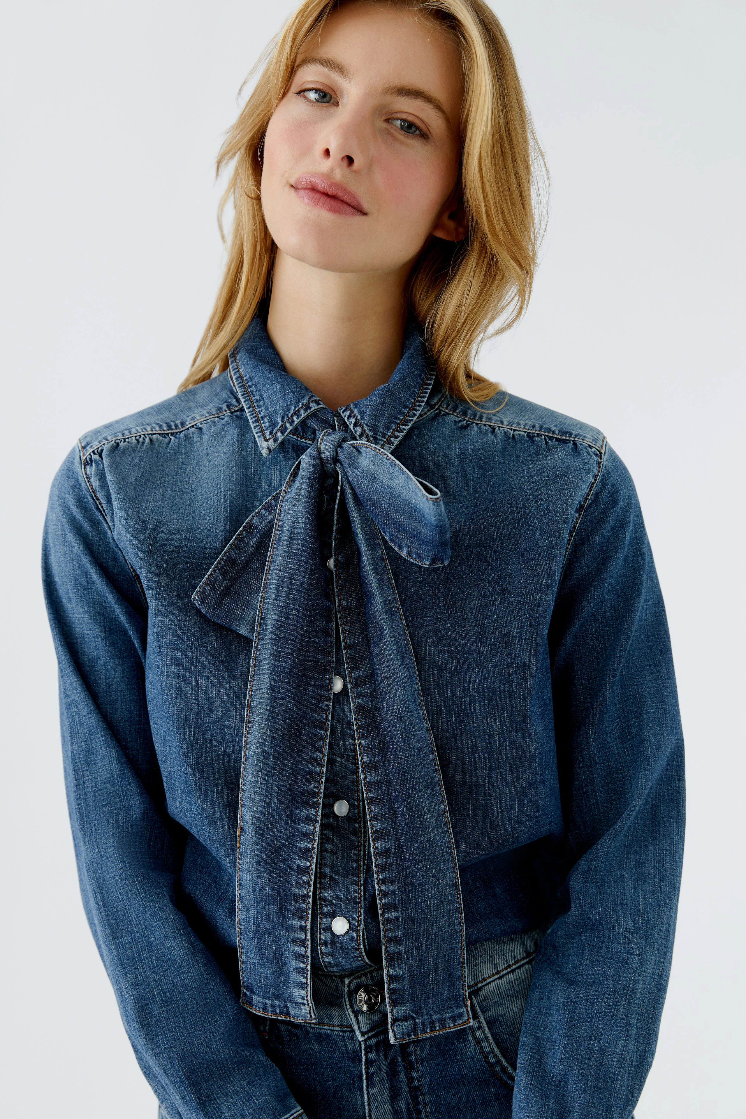 Casual women's denim shirt with a bow tie detail, worn by a woman with long hair.