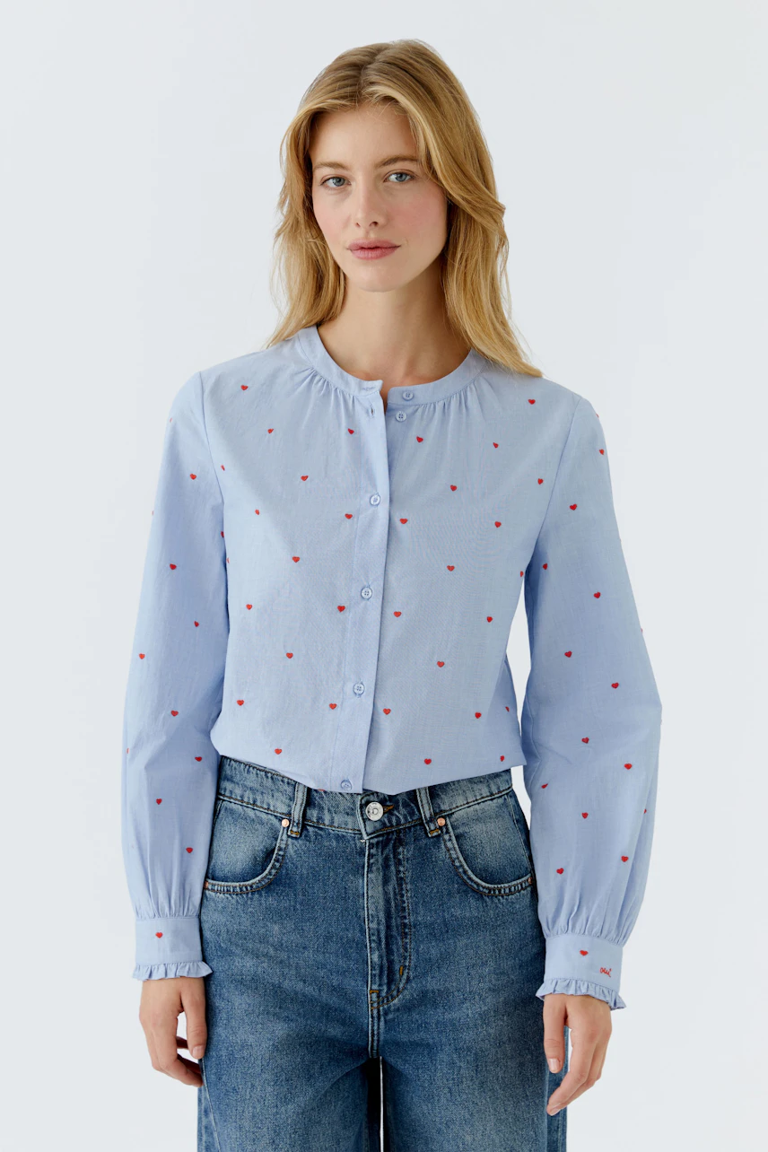 Light blue blouse with red dots: Woman wearing a button-up shirt with a relaxed fit.