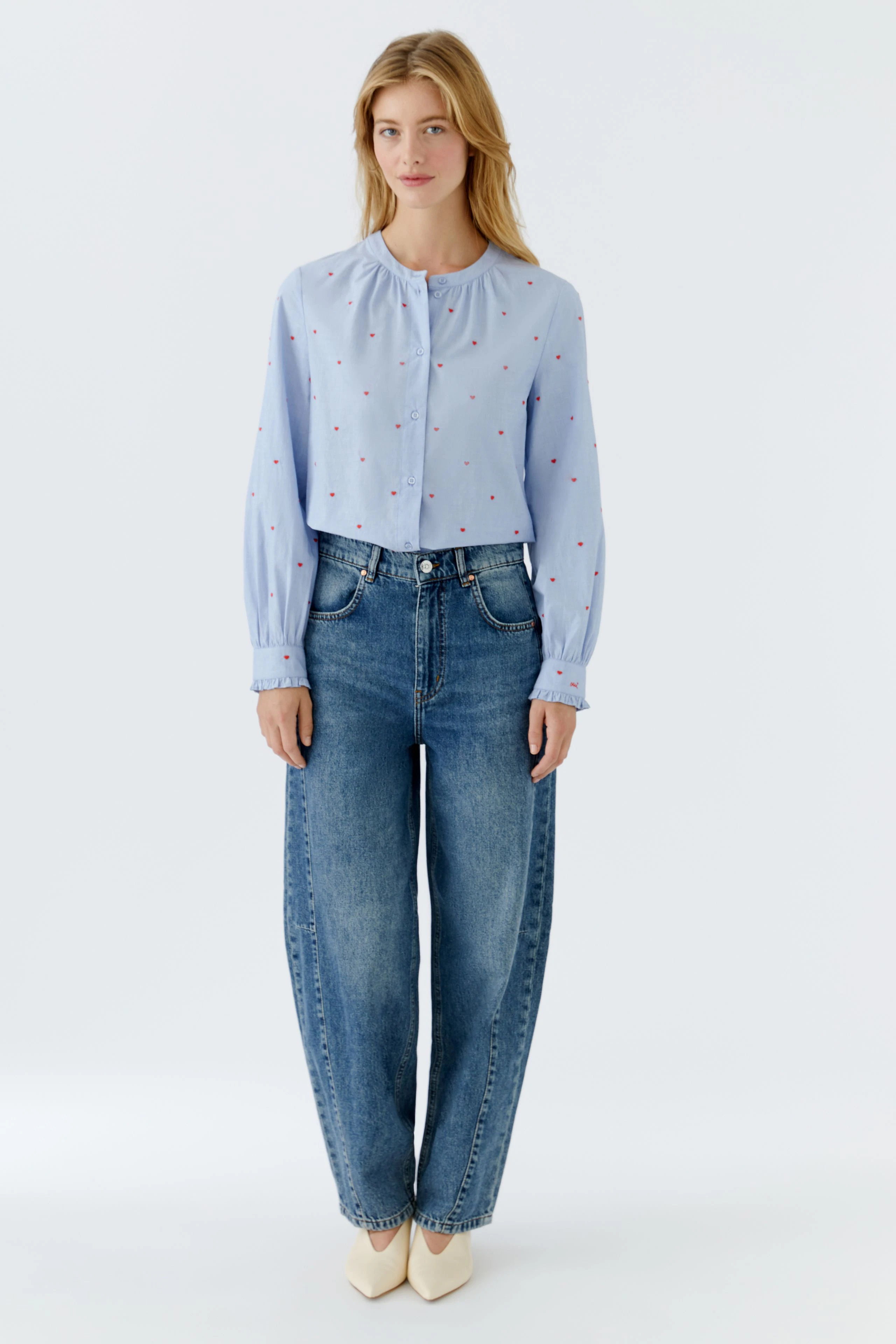 Casual women's blouse: A woman in a light blue blouse with small red dots and relaxed-fit jeans.