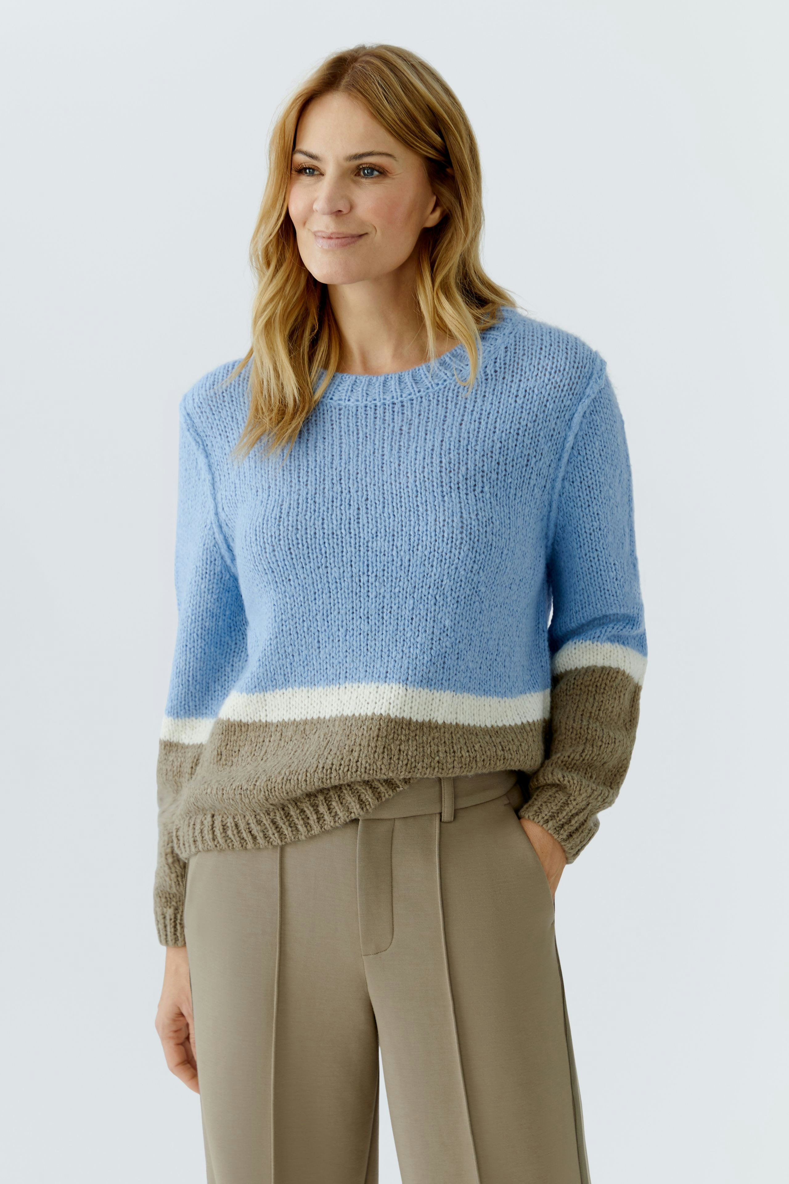 Casual women's pullover: A woman in a blue and beige striped pullover paired with beige trousers.