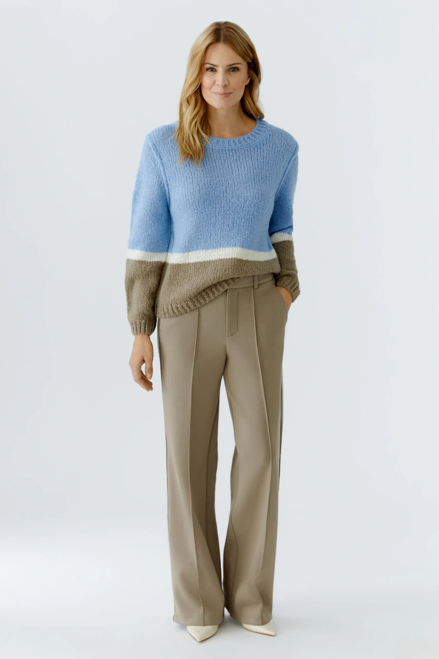 Casual women's pullover: Woman in a blue and brown striped pullover paired with beige trousers.