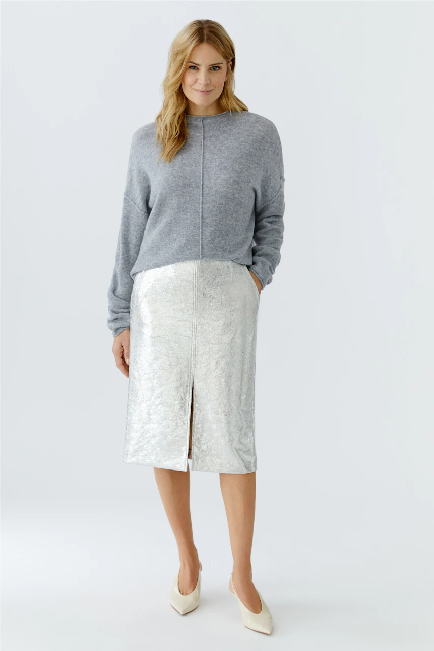 Casual women's pullover: A woman in a gray pullover paired with a shiny silver skirt.