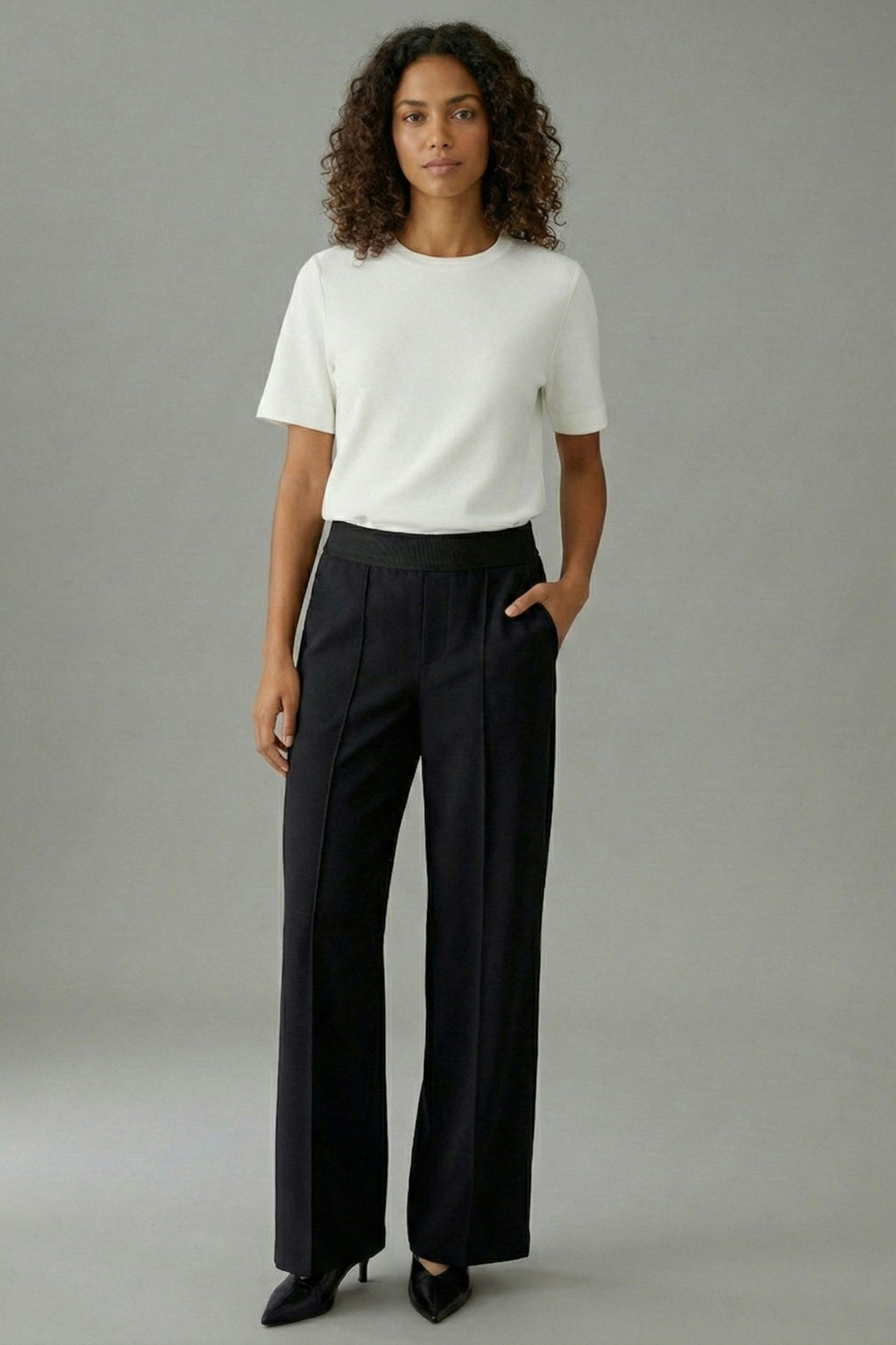 Casual women's trousers: A woman in black wide-leg trousers with a relaxed fit and a simple top.