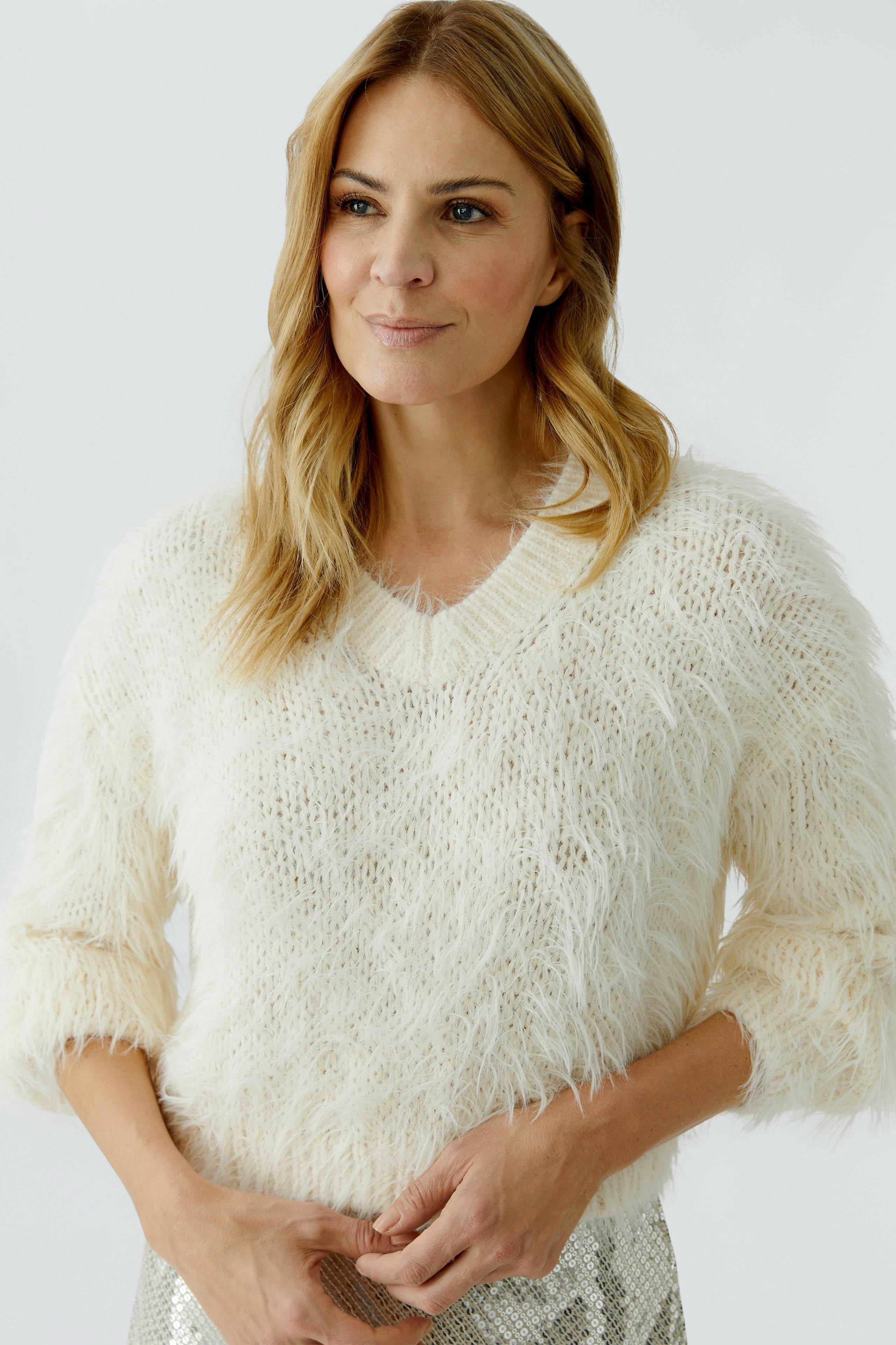 Cozy women's pullover: A woman in a fluffy cream pullover with three-quarter sleeves smiles softly.