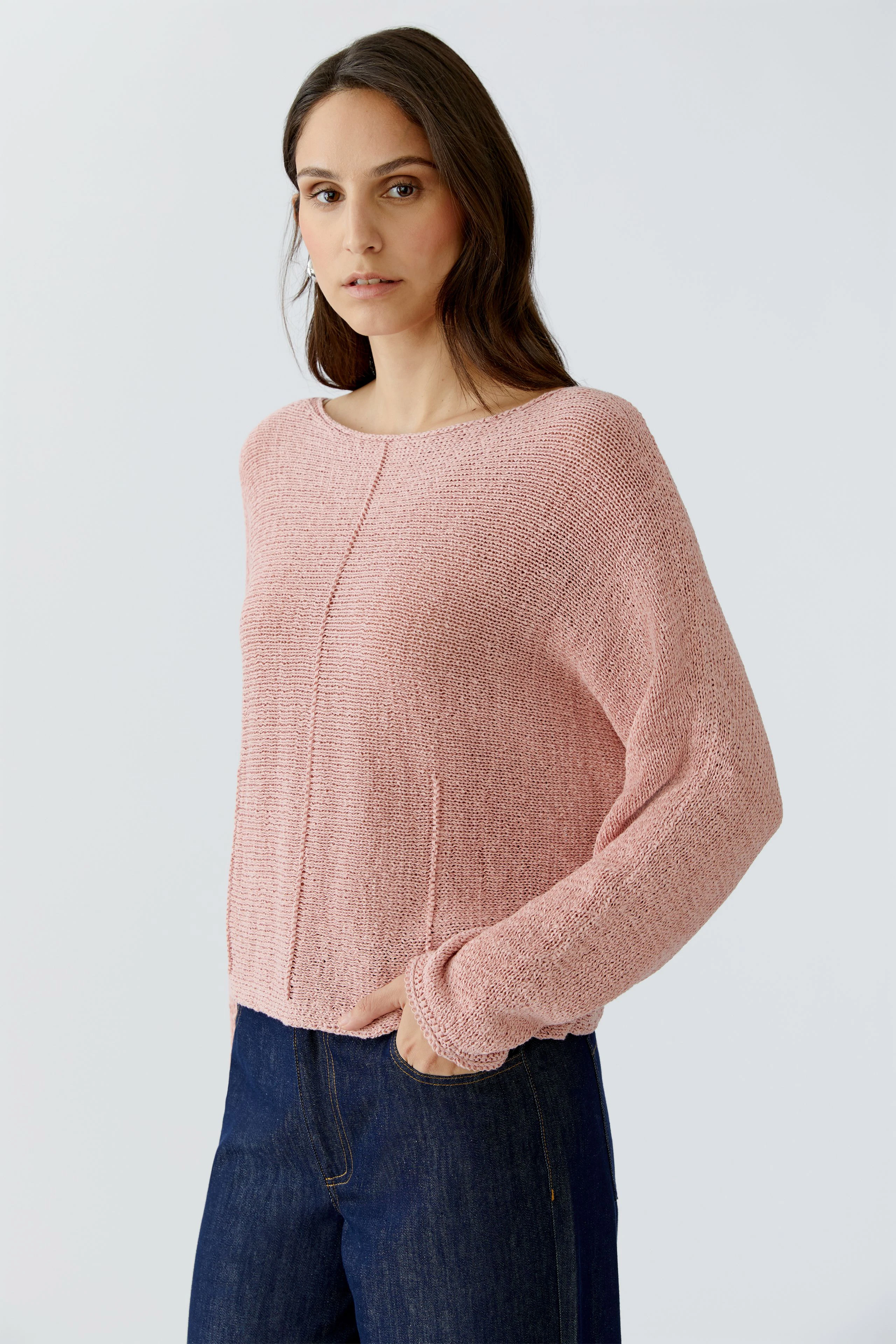Casual women's pullover: A woman in a light pink pullover with a relaxed fit and wide sleeves.