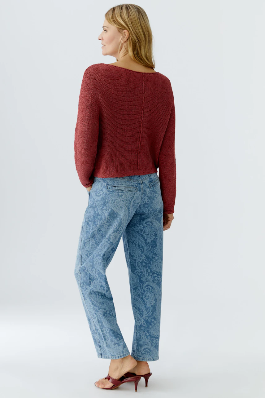 Damen-Pullover: Frau in rotem, lässigem Strickpullover mit lockerer Passform und Jeans.