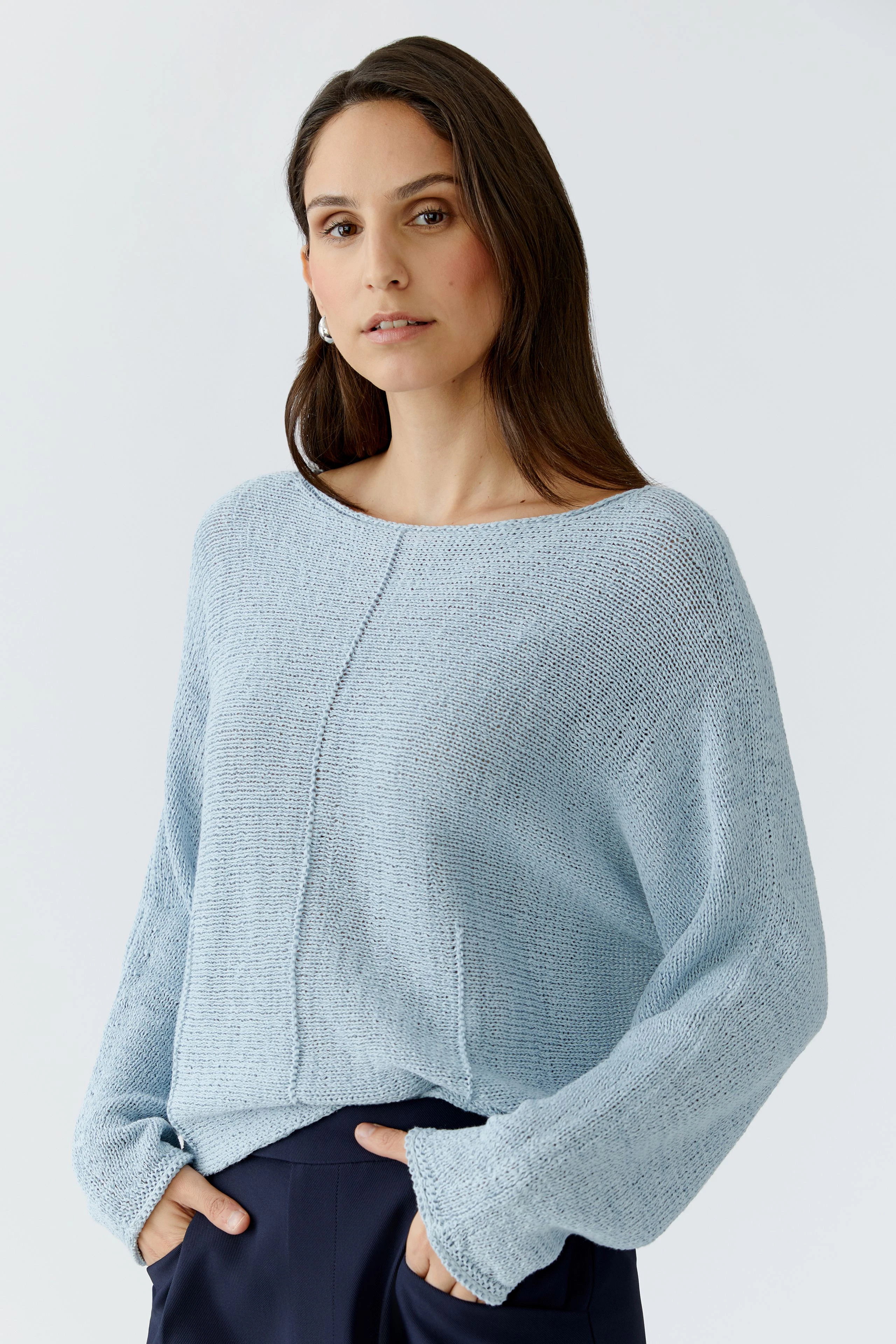 Damen-Pullover: Frau in hellblauem, lässigem Strickpullover mit weitem Schnitt und langen Ärmeln.