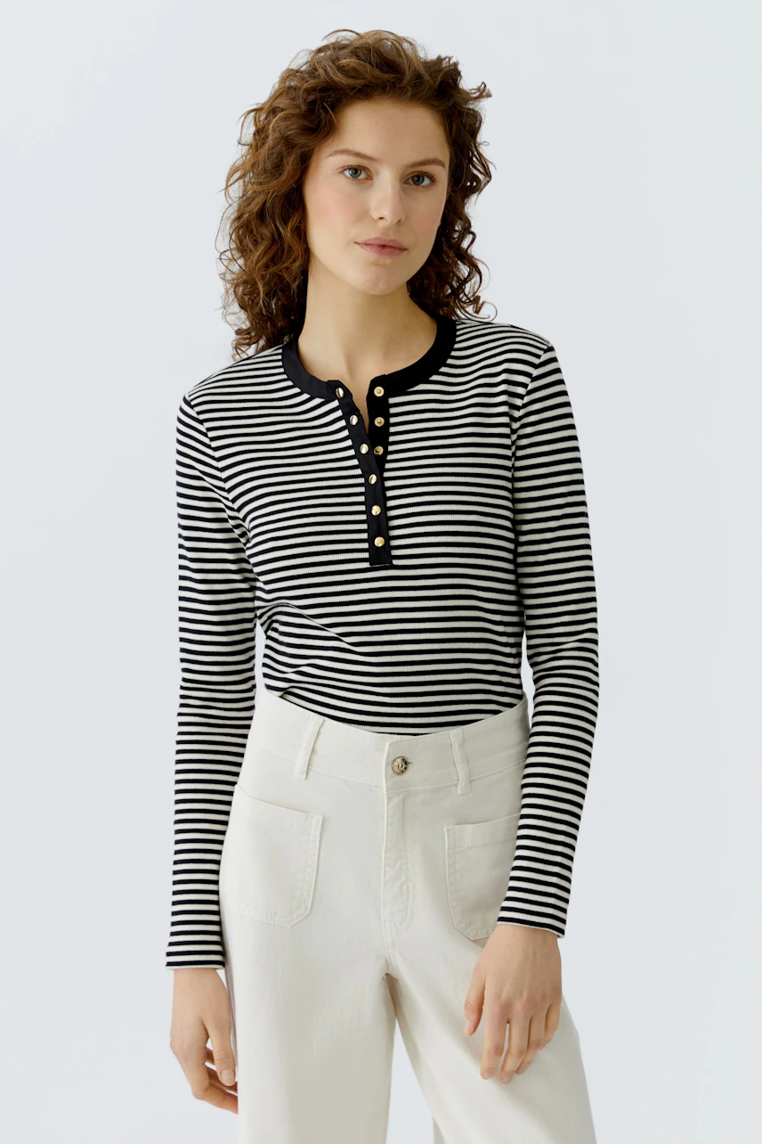 Casual women's long-sleeve shirt: A woman in a striped pullover with buttons, paired with light pants.