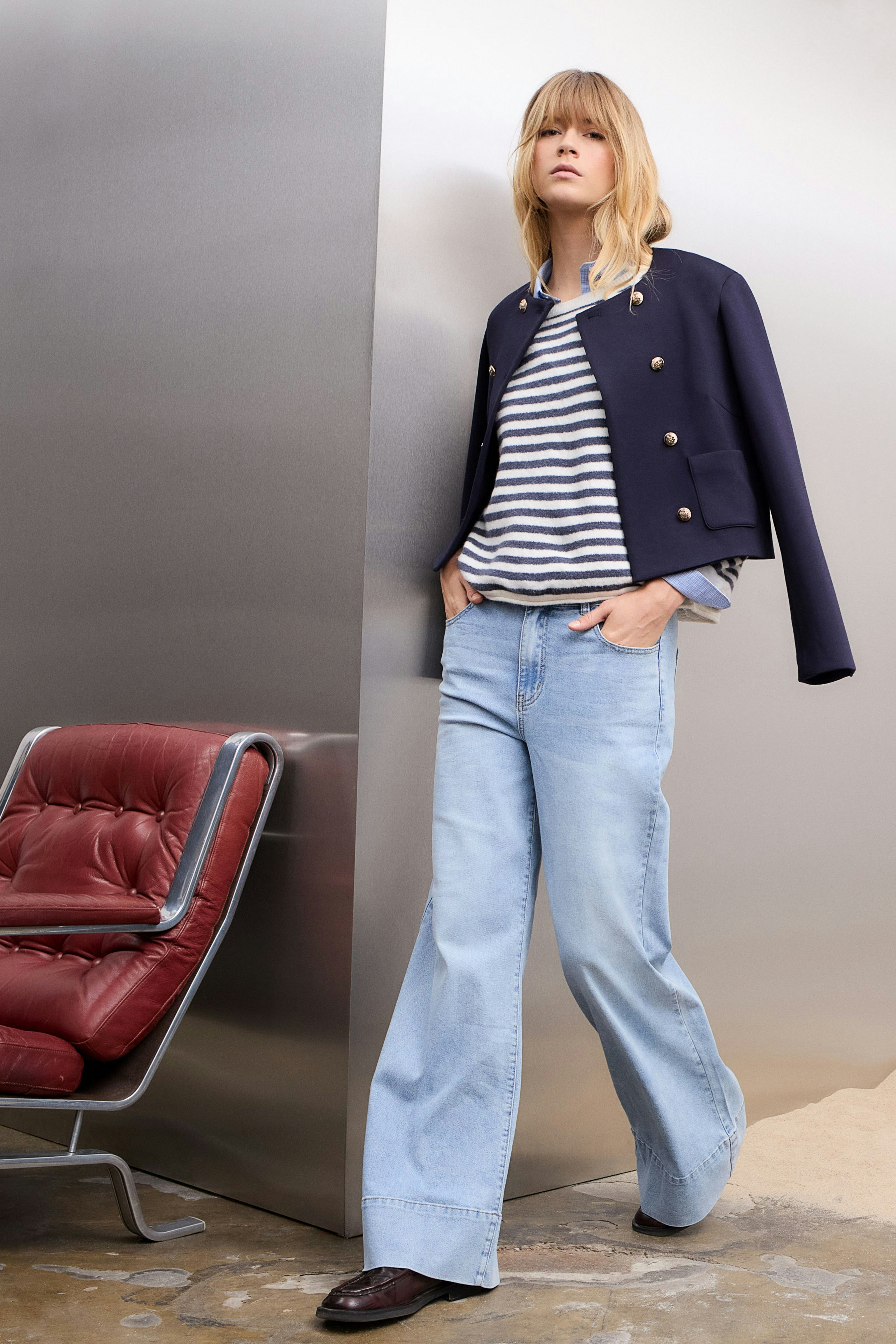 Wide leg jeans: A woman stands confidently in light blue wide leg jeans, paired with a brown pullover.
