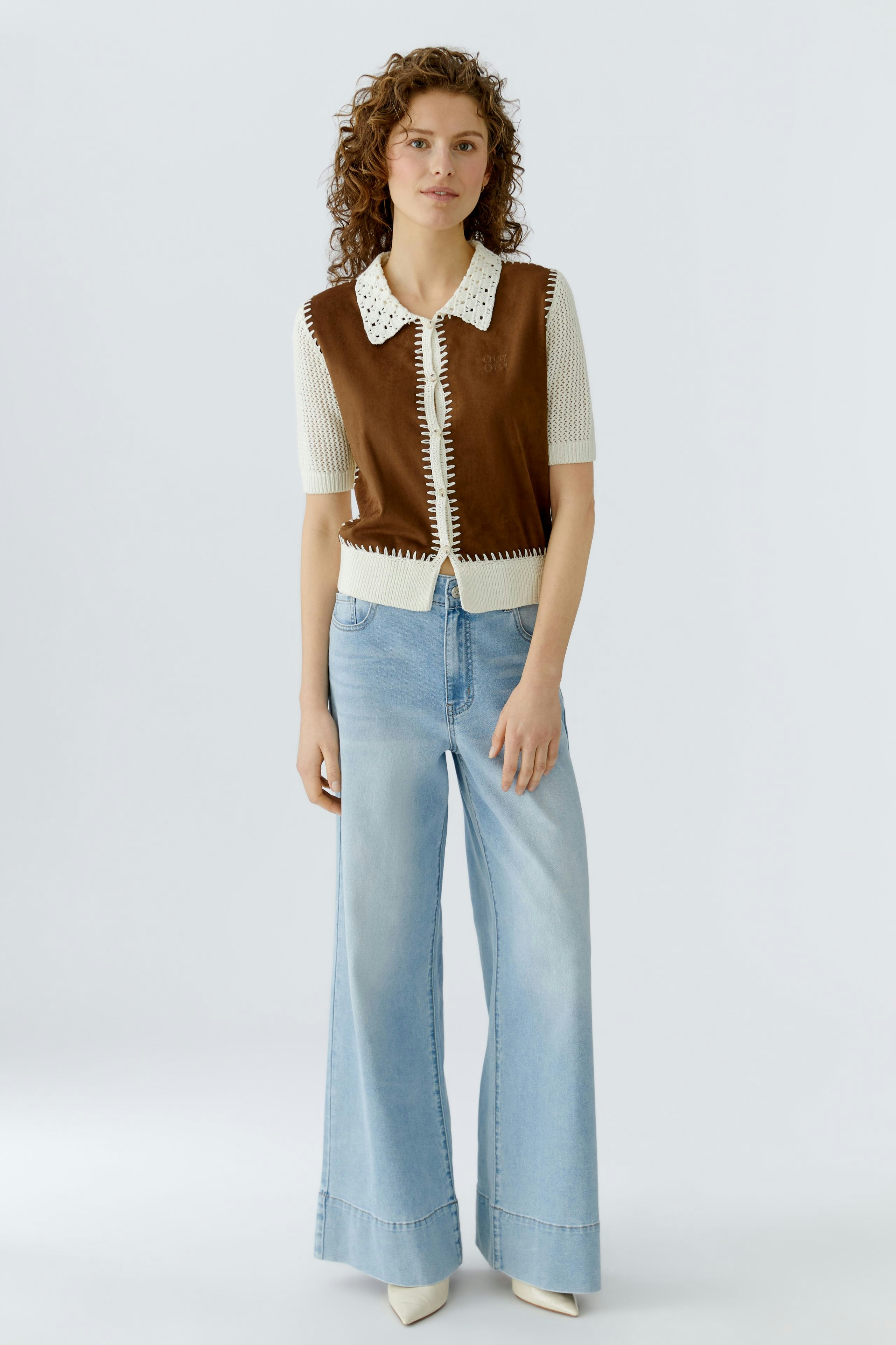 Damen-Strickjacke: Frau trägt eine braune Strickjacke mit Kragen und lässigen Jeans.