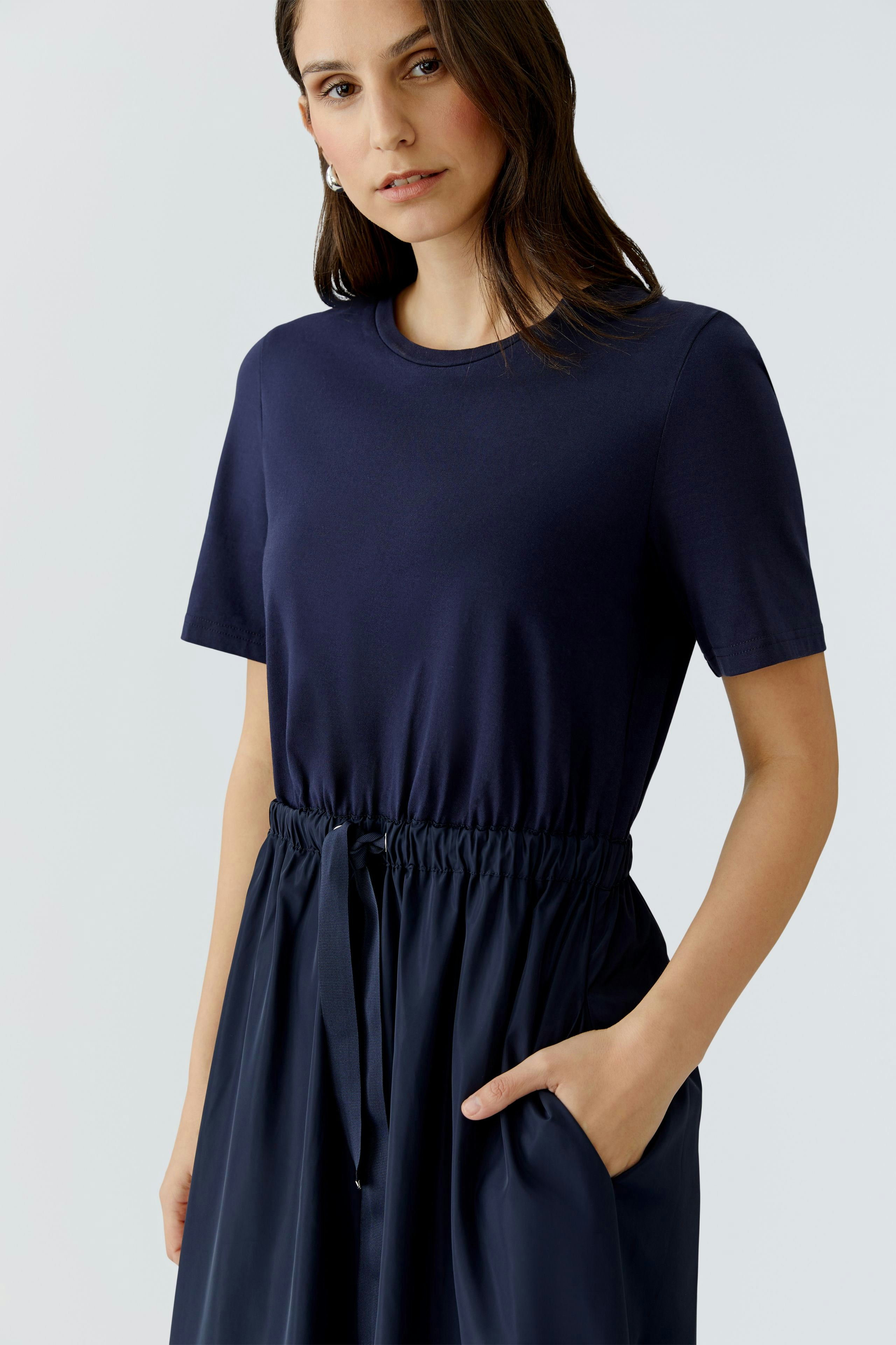 Casual maxi dress: Woman in a navy top with an elastic waist and flowing skirt, featuring side pockets.
