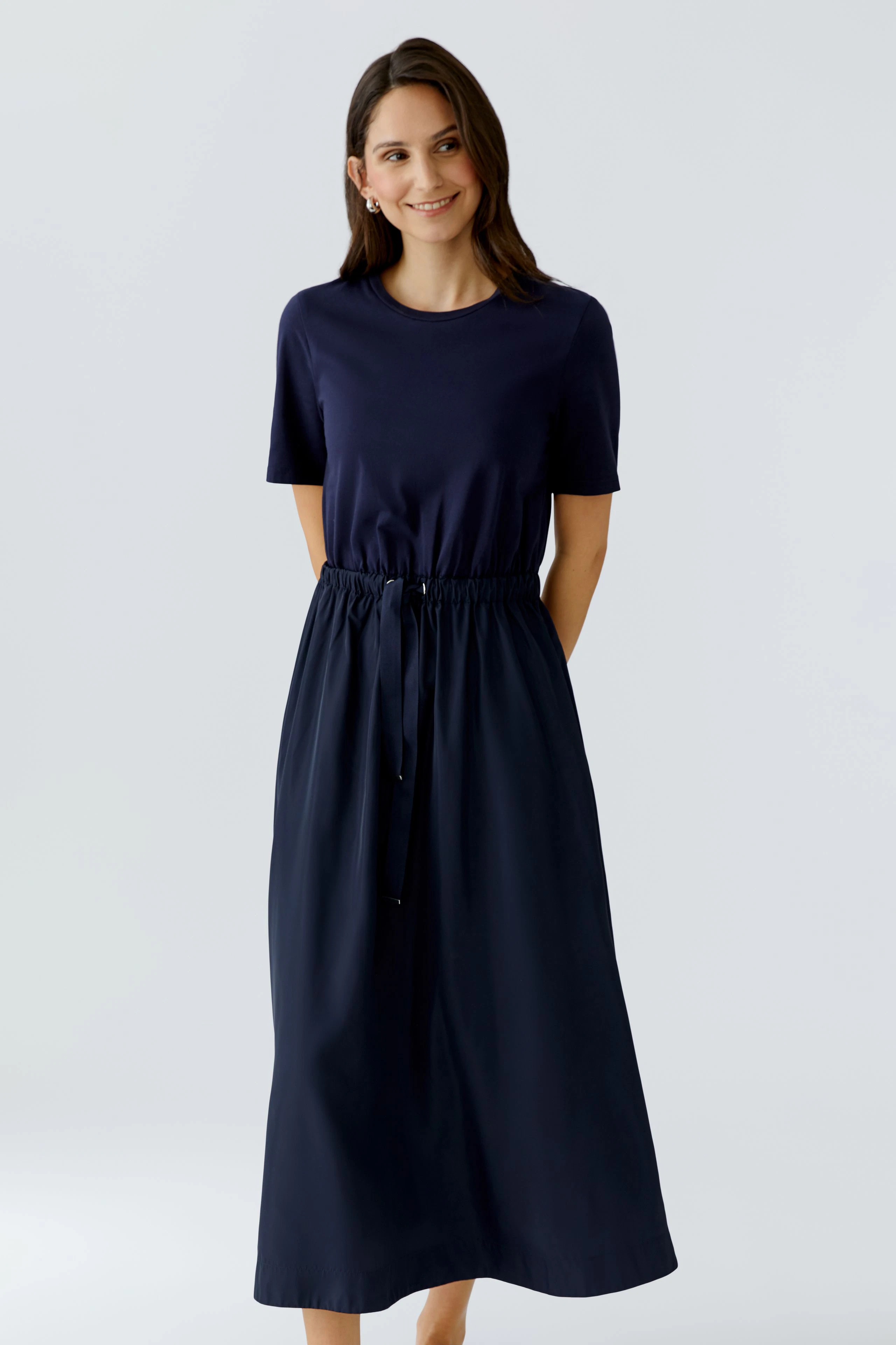 Casual maxi dress: Woman in a navy dress with a drawstring waist and short sleeves, smiling confidently.