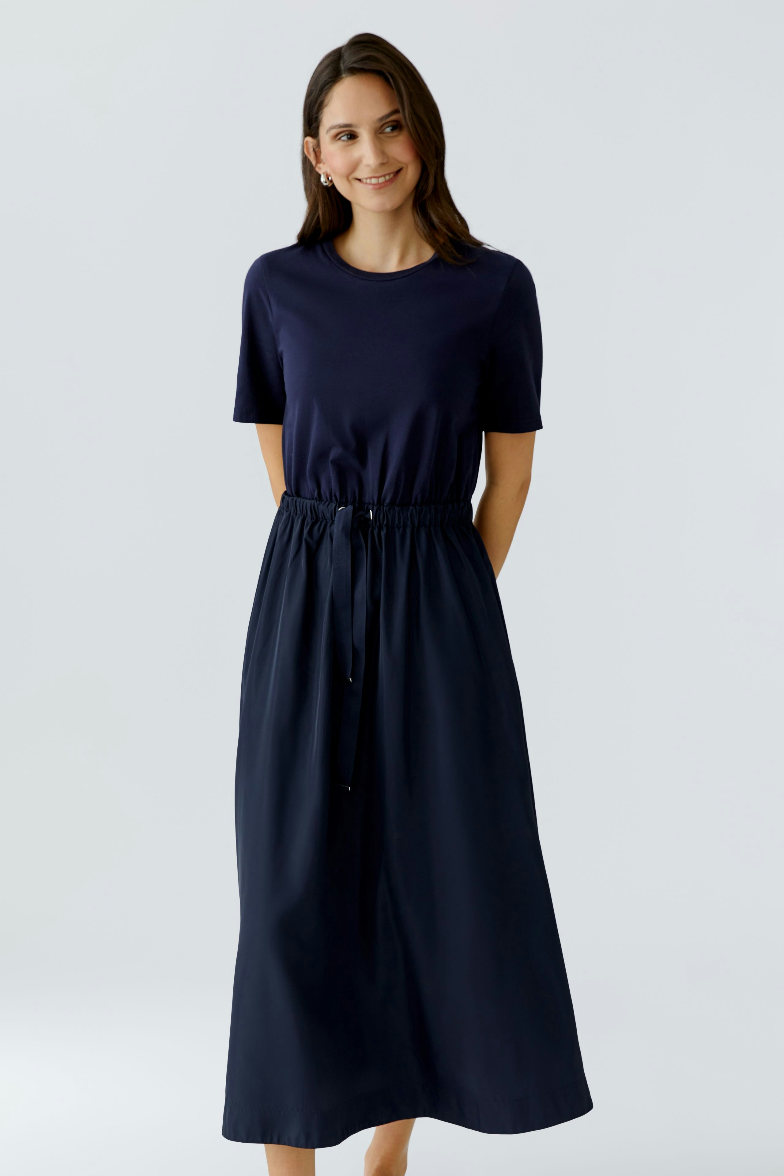 Casual maxi dress: Woman in a navy dress with a drawstring waist and short sleeves, smiling confidently.