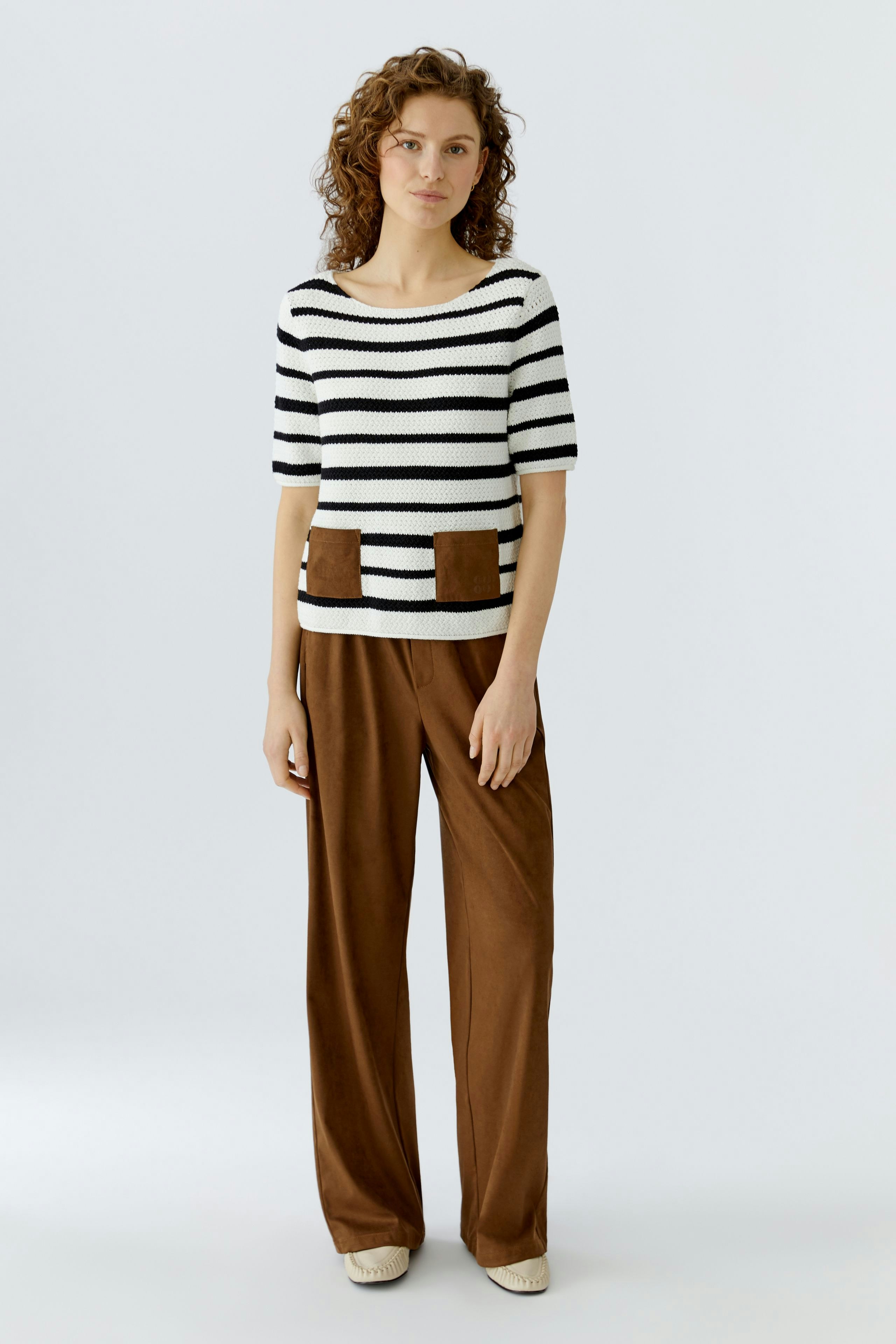 Casual women's pullover: A woman in a striped pullover with pockets and relaxed fit pants.