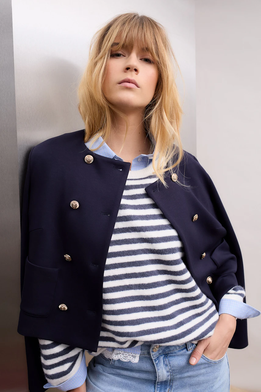 Casual women's shirt blouse: Woman in a striped pullover and navy jacket poses confidently.