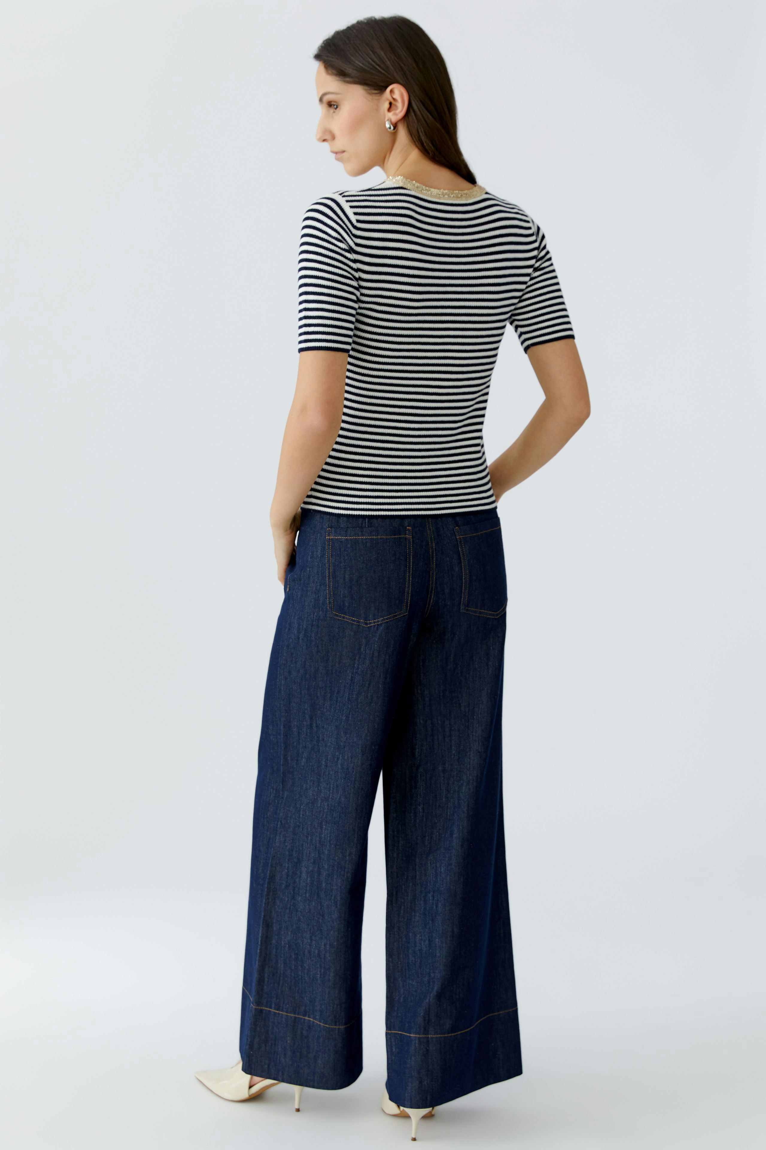 Casual women's pullover: Young woman in a striped pullover and wide-leg jeans, showcasing a relaxed style.
