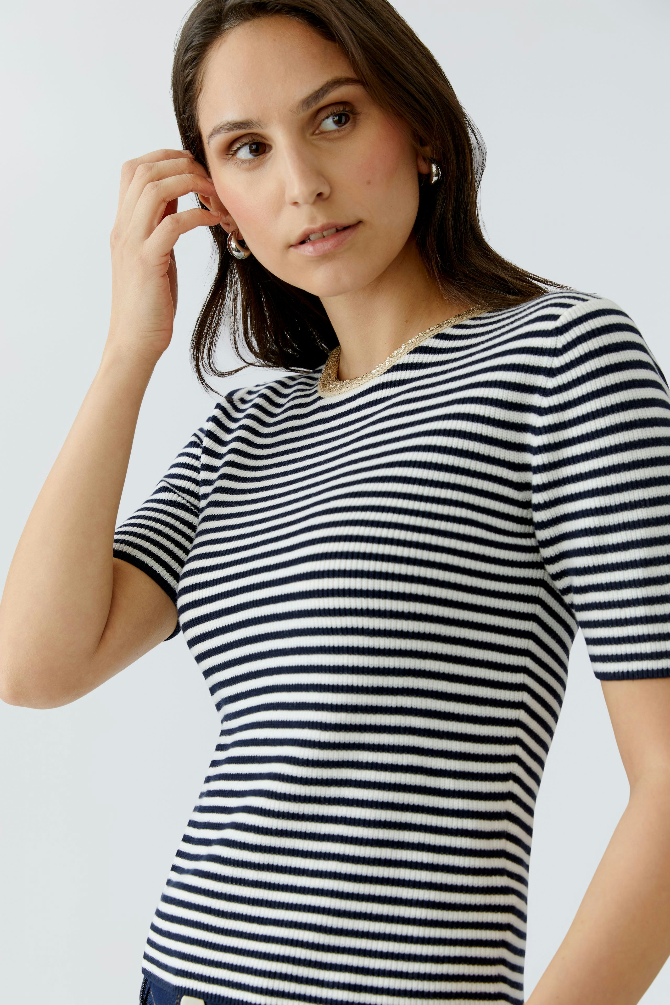 Casual women's pullover: Young woman in a striped short-sleeve pullover, looking thoughtfully.