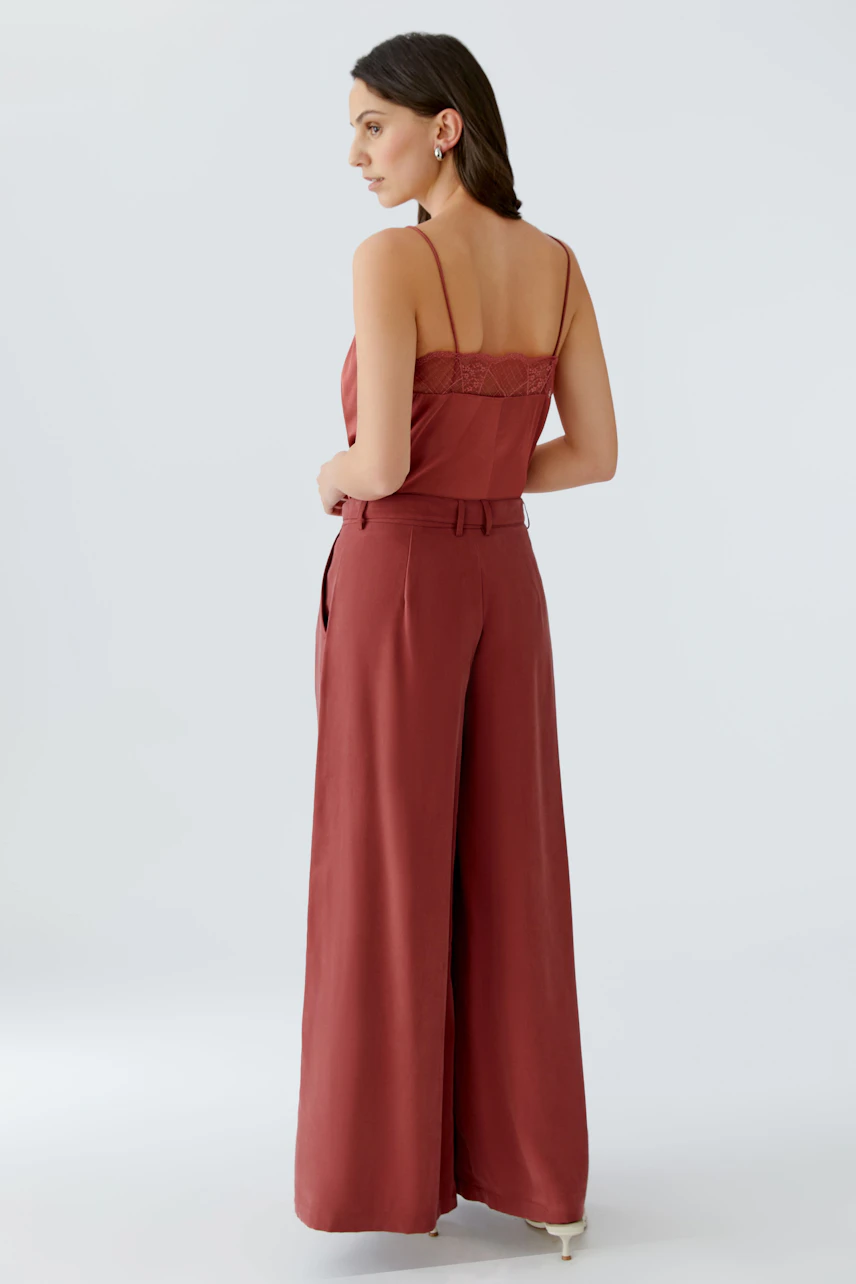 Wide-leg trousers: A woman in rust-colored, high-waisted trousers with a relaxed fit, showcasing a stylish look.