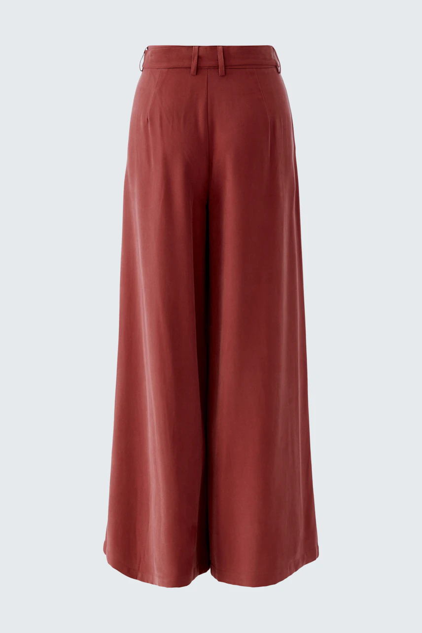 Wide-leg trousers: A woman in rust-colored wide-leg trousers stands confidently.