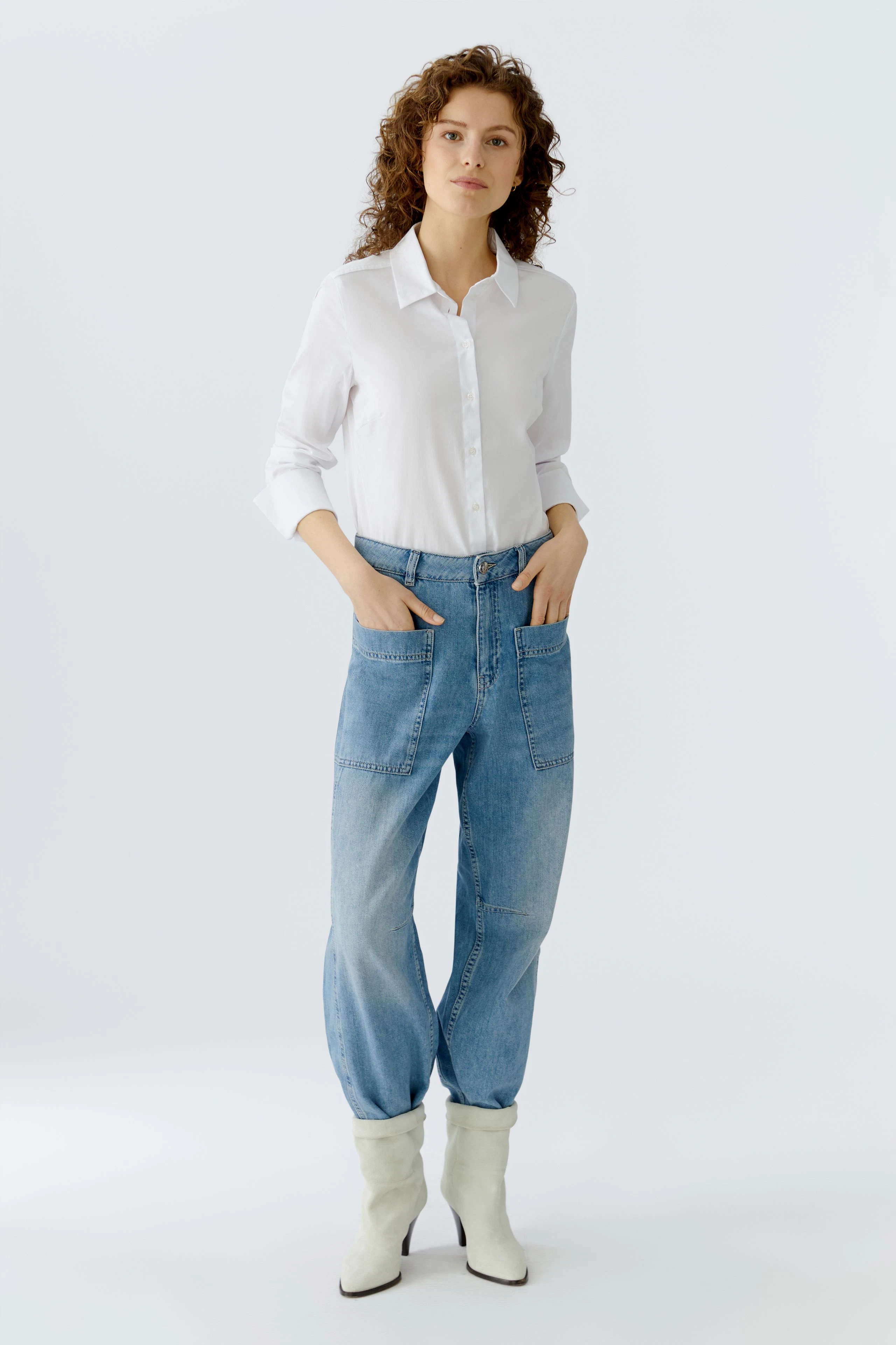 Bequeme Jeans Barrel: Frau in lässigen, hellblauen Jeans mit weitem Schnitt und weißen Bluse.