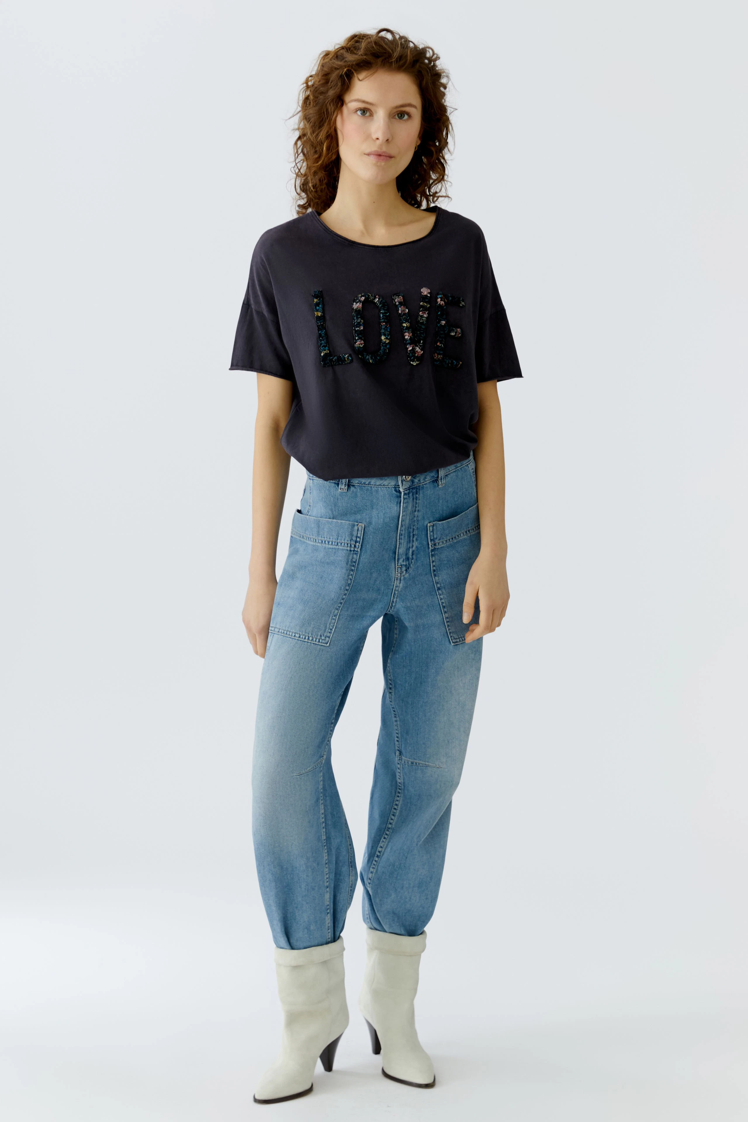 Casual women's T-shirt: Young woman in a navy tee with 'LOVE' design, paired with light blue jeans.