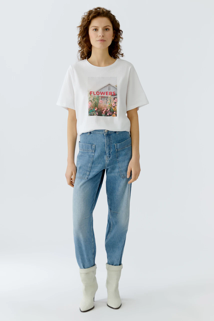 Casual women's T-shirt: A woman in a white tee with a floral print, paired with relaxed jeans.
