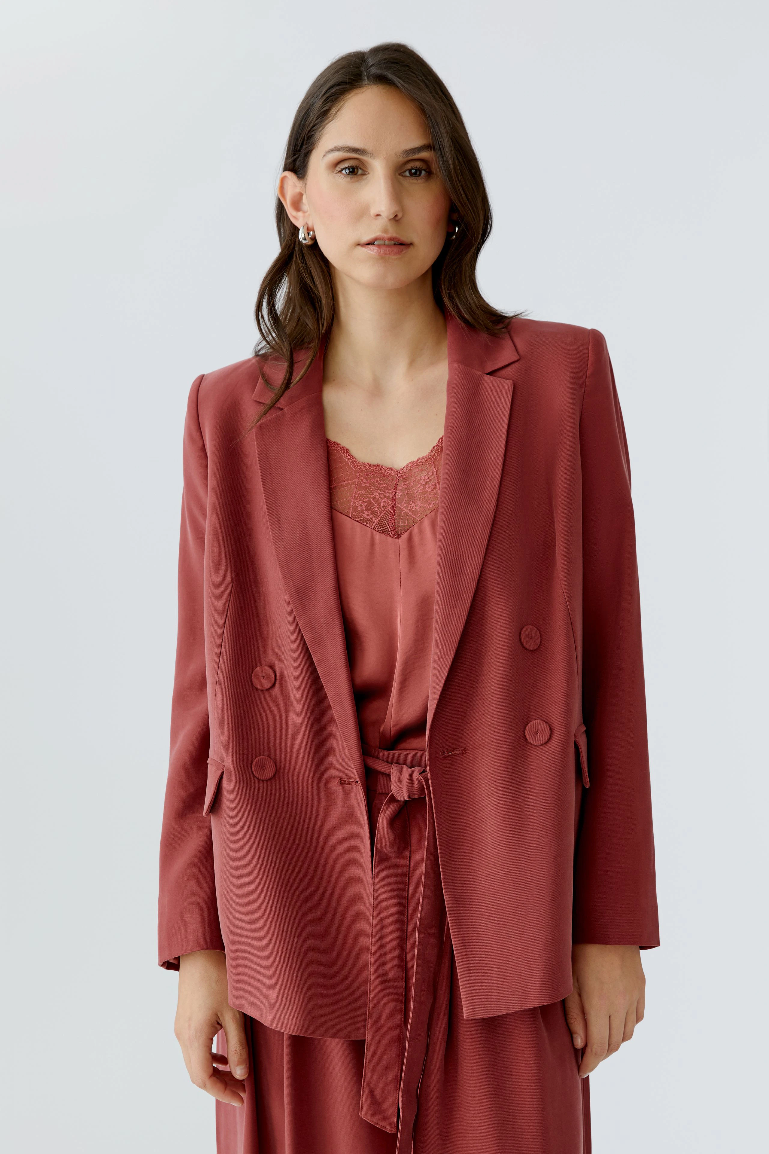 Damen-Blazer in warmem Rot: Frau trägt einen lässigen Blazer mit doppelter Knopfleiste und Bindegürtel.