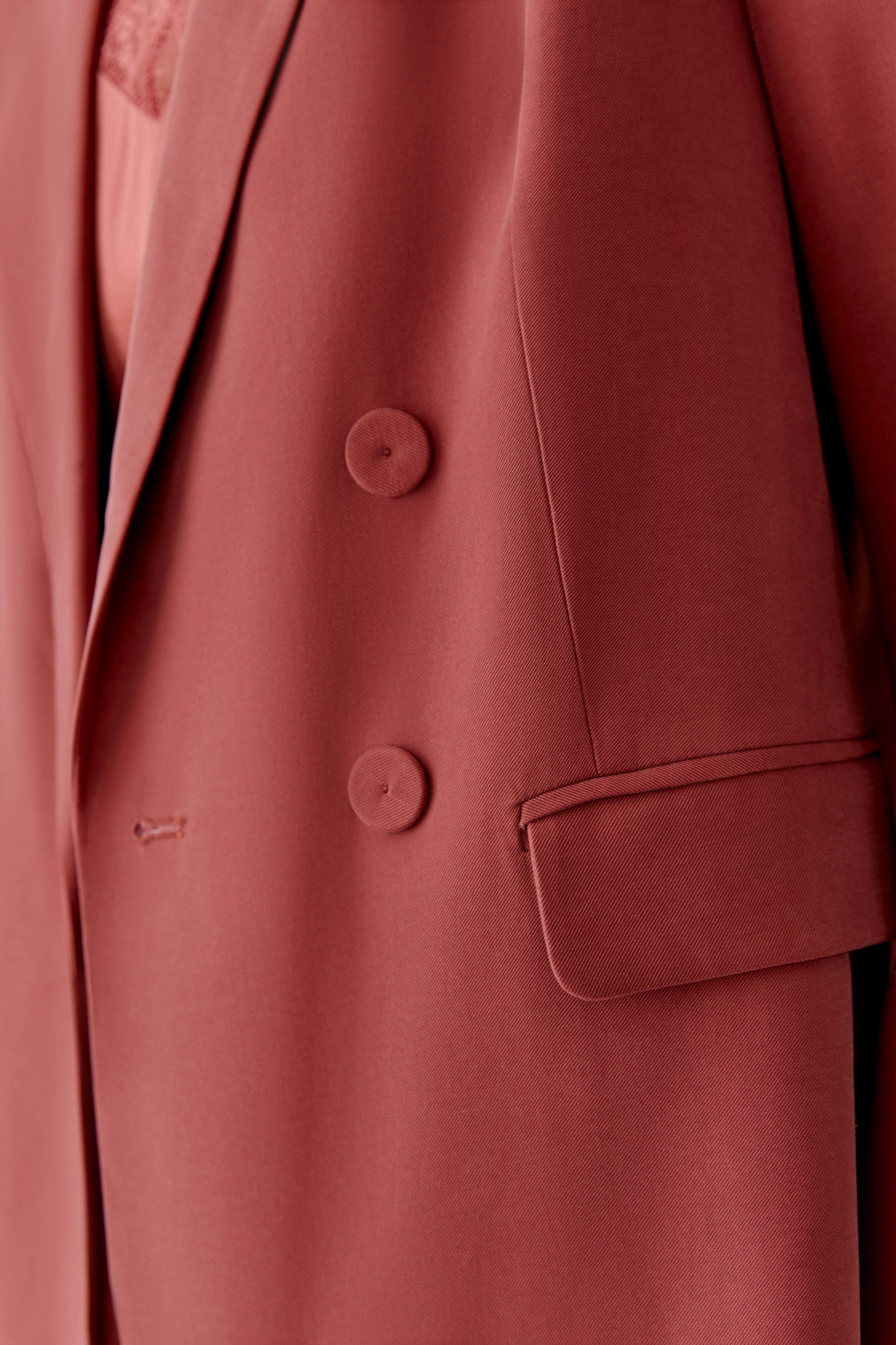 Modischer Damen-Blazer in warmem Rot mit doppelter Knopfleiste und lässigem Schnitt.