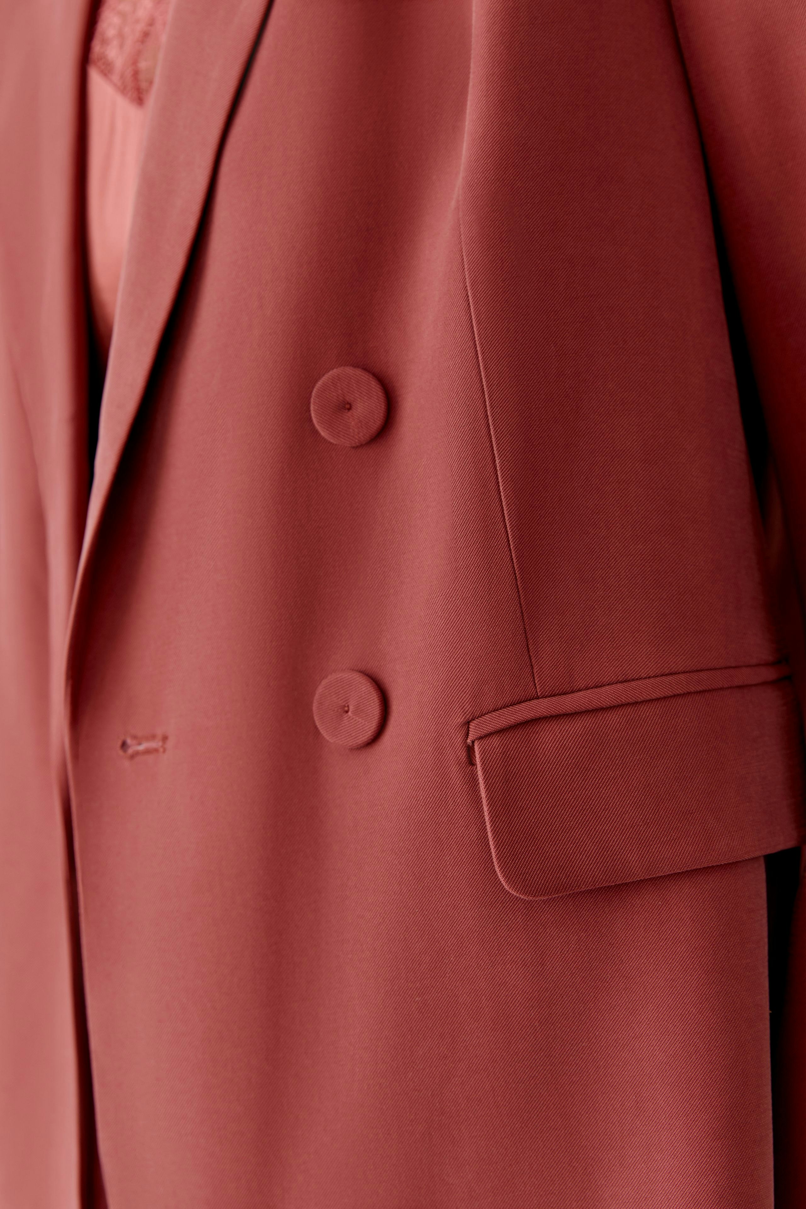 Modischer Damen-Blazer in warmem Rot mit doppelter Knopfleiste und lässigem Schnitt.