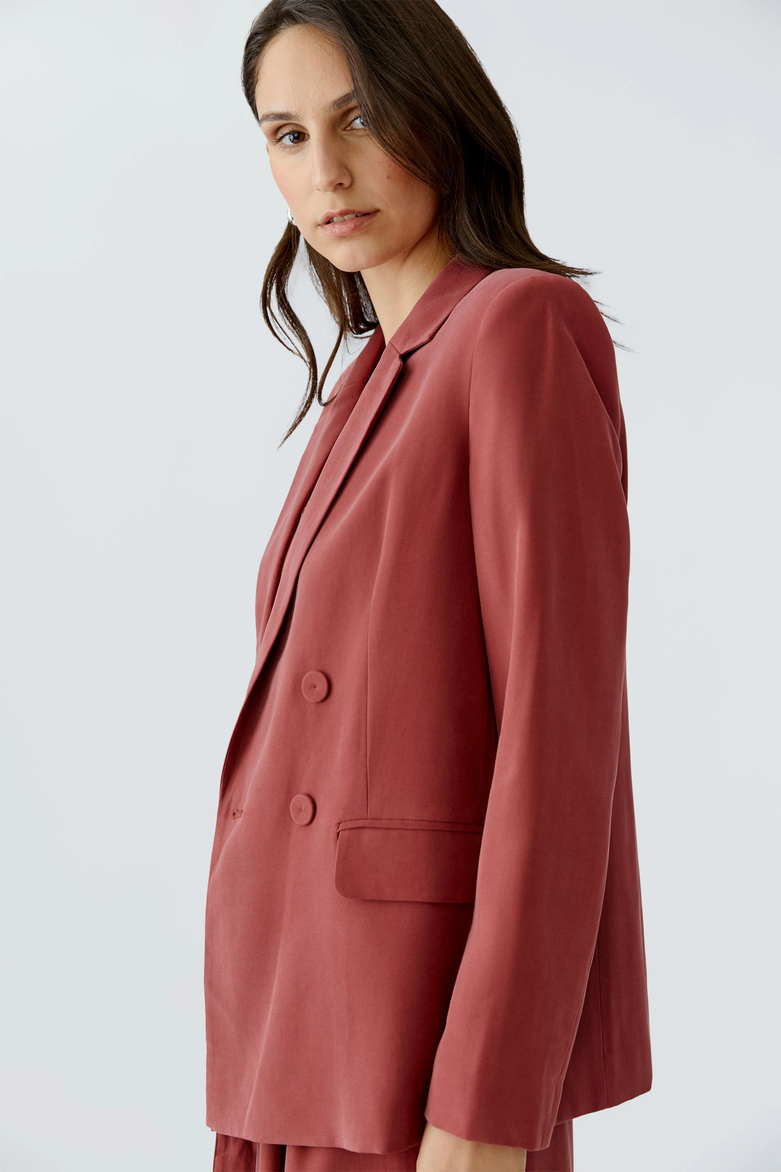 Modischer Damen-Blazer: Frau in einem rosafarbenen Blazer mit doppelter Knopfleiste und lässigem Schnitt.