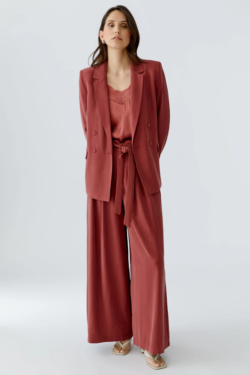 Modischer Damen-Blazer: Frau in einem rosafarbenen Blazer mit lässigem Schnitt und passender Hose.