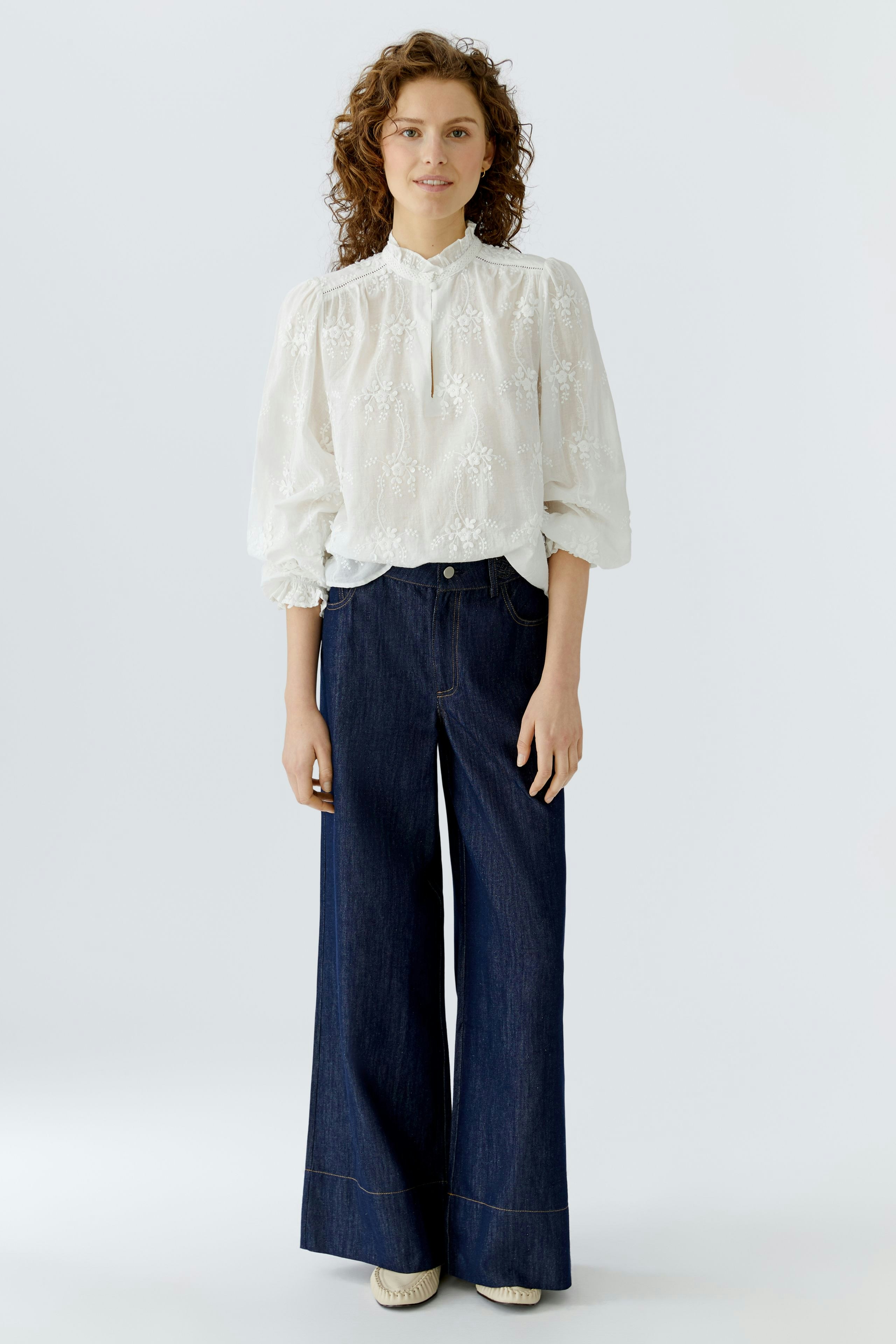 Lightweight women's blouse with floral embroidery, paired with wide-leg jeans.
