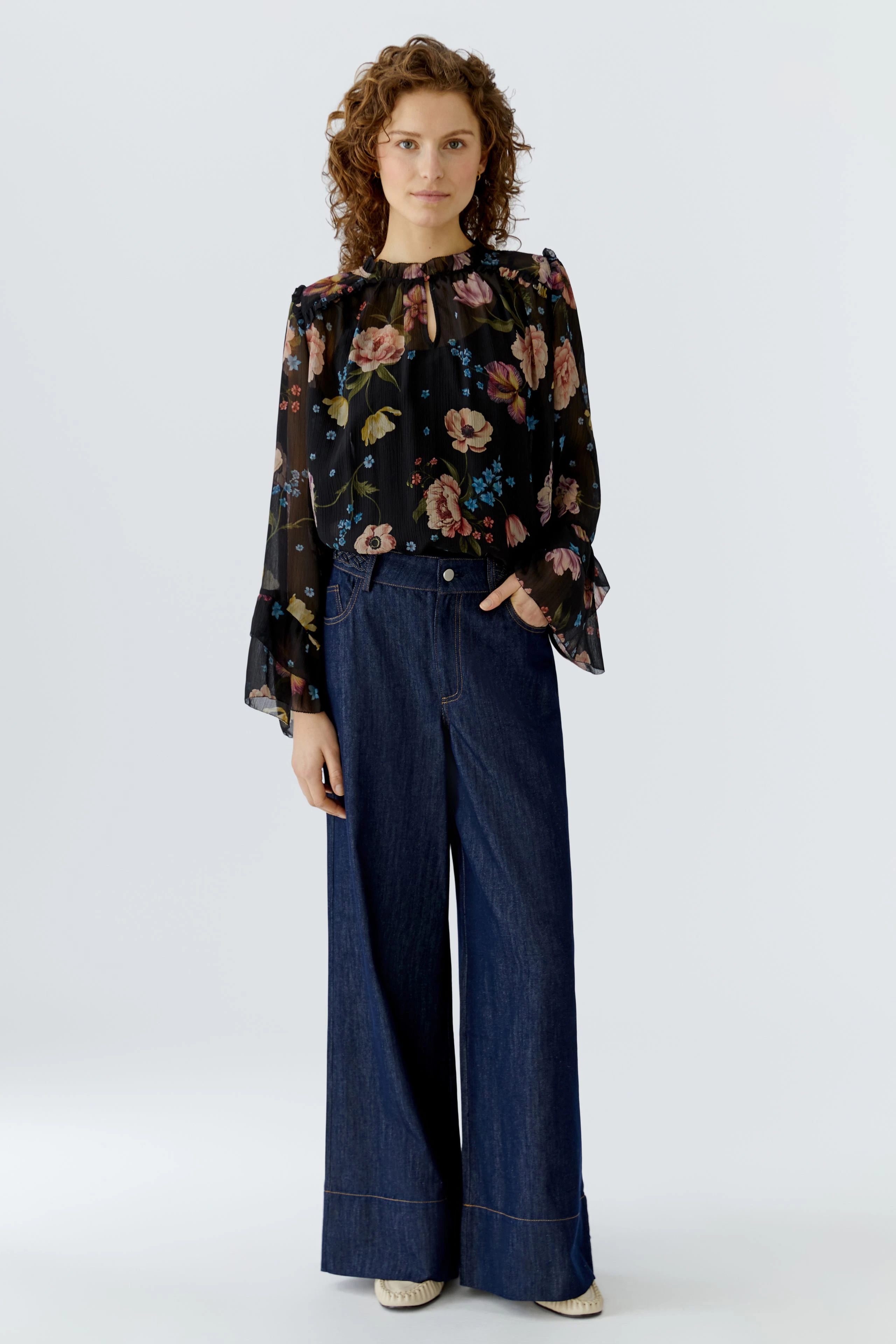 Floral blouse: A woman in a sheer black blouse with colorful floral patterns and a gathered neckline.