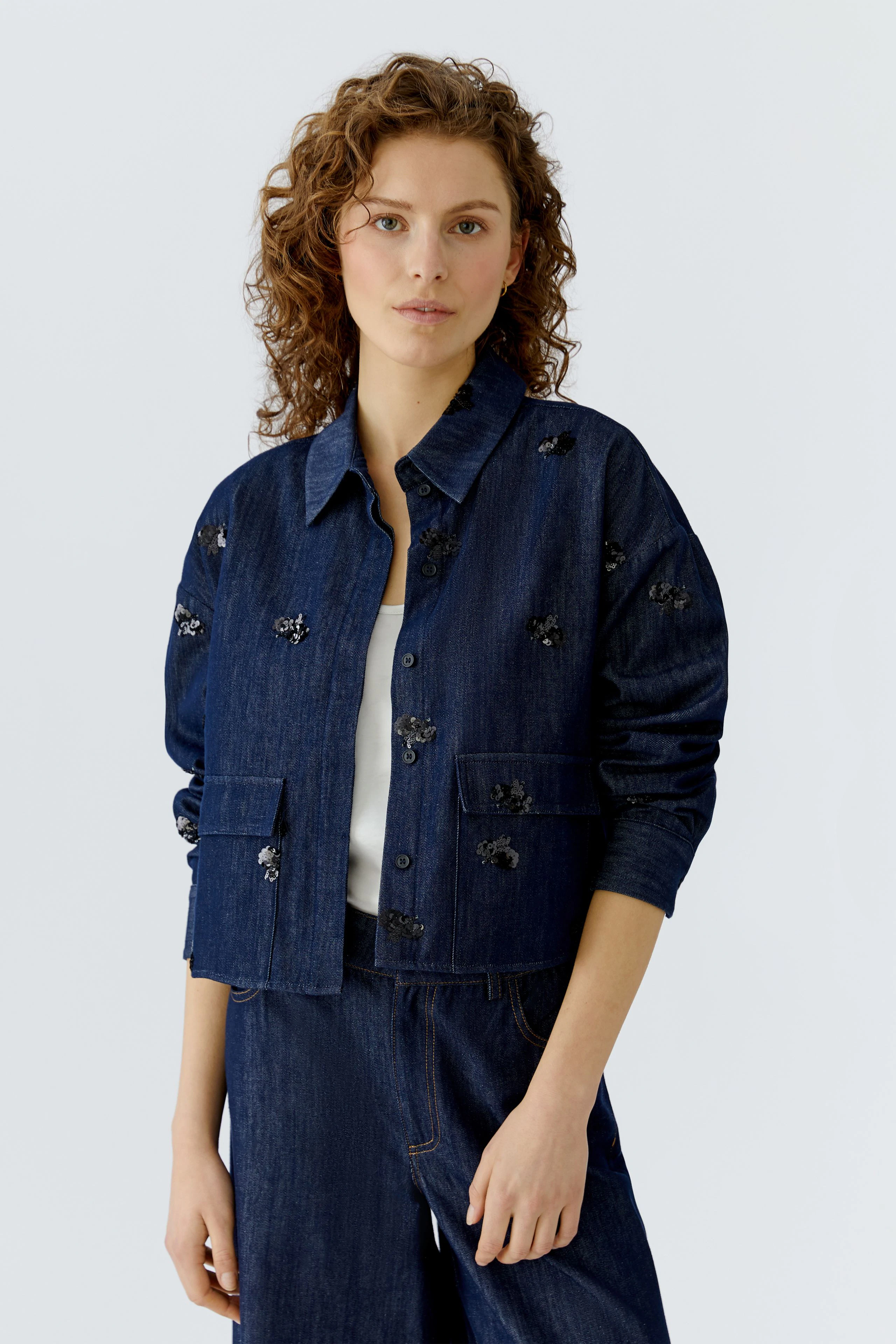 Casual women's jacket: A woman in a dark denim jacket with floral embroidery, styled effortlessly.