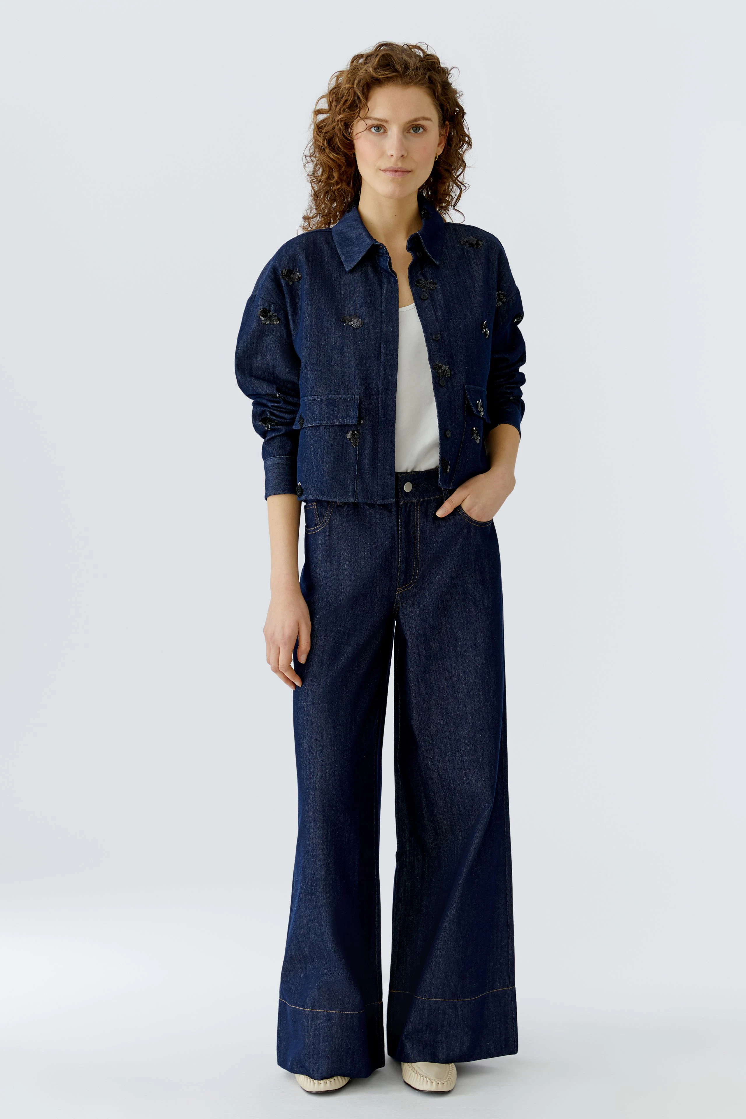 Casual women's jacket: A woman in a denim jacket with floral details, paired with wide-leg jeans.