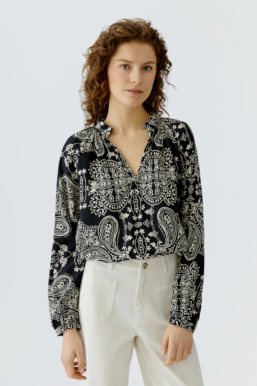 Casual women's blouse: A woman in a black and white patterned blouse with a relaxed fit.