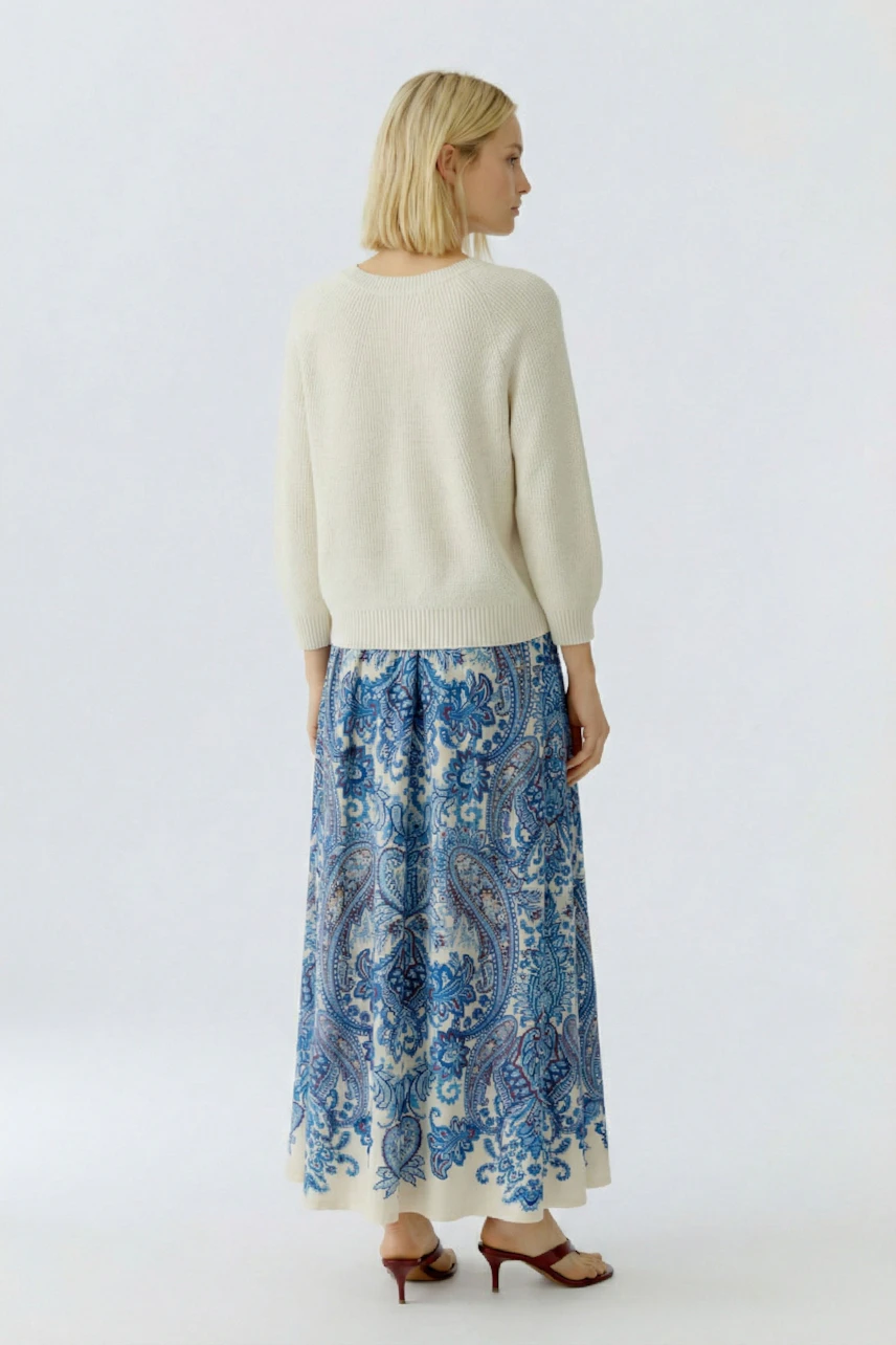 Casual women's pullover: A woman in a light pullover paired with a colorful patterned skirt.